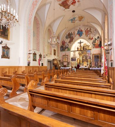 Zdjęcie nr 12: Kościół orientowany, murowany z cegły i kamienia, jednonawowy, na rzucie wydłużonego prostokąta z prezbiterium zamkniętym trójbocznie, wieżą na osi, zakrystią przy północnej ścianie prezbiterium, kruchtą przy południowej ścianie nawy i kaplicą od północy. Nawa pięcioprzęsłowa, ściany gładkie, sklepienie kolebkowe z lunetami, gurt między drugim, a trzecim przęsłem, pięć okien po stronie południowej, po północnej blendy odpowiadające wielkością i kształtem przeciwległym otworom okiennym. Prezbiterium oddzielone ścianą tęczową przeprutą łukiem o kształcie lekko zaostrzonym, dwuprzęsłowe, o sklepieniu krzyżowym, z dwoma ostrołukowymi oknami w ścianie południowej; zakrystia o sklepieniu sieciowym/gwiaździstym. Od zachodu chór wsparty arkadami z łukami o profilu lekko zaostrzonym, z balustradą zdobioną motywem rombu wypełnionego czworoliściem. Pod chórem skarbiec. Wejście główne od zachodu, boczne od południa z kruchtą (w nim kamienny portal z 1673 roku), kolejne od zakrystii, między zakrystią, a prezbiterium gotycki ostrołukowy portal z żelaznymi drzwiami z kratownicą rombową. 
Fasada wieżowa, z wejściem na osi po czterech stopniach. Przedsionek zwieńczony trójkątnym przyczółkiem z zatkniętym na szczycie krzyżem łacińskim. Drzwi zamknięte półkoliście, ponad nimi płaskorzeźba z przedstawieniem głowy Chrystusa otoczonej winną latoroślą. 
Wieża trójkondygnacyjna, zwieńczona trójkątnym przyczółkiem; w dolnej kondygnacji okulus, w środkowej okno zamknięte półkoliście, w ostatniej zegar w niszy powtarzającej kształt okna poniżej. 
Bryła rozczłonkowana; całość budynku obiega cokół, fragmentami kamienny, elewacje boczne oraz prezbiterium wsparte przyporami. Trzy przęsła nawy głównej otynkowane, reszta z cegły. Dachy dwuspadowe, nad pierwszymi dwoma przęsłami nawy niższy niż nad pozostałymi. Nad czwartym przęsłem nawy wieloboczna wieżyczka na sygnaturkę przepruta arkadami, przykryta dachem ostrosłupowym zakończonym kulą z krzyżem łacińskim.  
Do najcenniejszego wyposażenia kościoła należą: ołtarz główny z obrazem Ukrzyżowanego Chrystusa pędzla Jana Triciusa oraz słynący cudami obraz Matki Boskiej w ołtarzu bocznym. 
