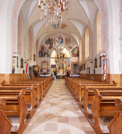 Zdjęcie nr 10: Kościół orientowany, murowany z cegły i kamienia, jednonawowy, na rzucie wydłużonego prostokąta z prezbiterium zamkniętym trójbocznie, wieżą na osi, zakrystią przy północnej ścianie prezbiterium, kruchtą przy południowej ścianie nawy i kaplicą od północy. Nawa pięcioprzęsłowa, ściany gładkie, sklepienie kolebkowe z lunetami, gurt między drugim, a trzecim przęsłem, pięć okien po stronie południowej, po północnej blendy odpowiadające wielkością i kształtem przeciwległym otworom okiennym. Prezbiterium oddzielone ścianą tęczową przeprutą łukiem o kształcie lekko zaostrzonym, dwuprzęsłowe, o sklepieniu krzyżowym, z dwoma ostrołukowymi oknami w ścianie południowej; zakrystia o sklepieniu sieciowym/gwiaździstym. Od zachodu chór wsparty arkadami z łukami o profilu lekko zaostrzonym, z balustradą zdobioną motywem rombu wypełnionego czworoliściem. Pod chórem skarbiec. Wejście główne od zachodu, boczne od południa z kruchtą (w nim kamienny portal z 1673 roku), kolejne od zakrystii, między zakrystią, a prezbiterium gotycki ostrołukowy portal z żelaznymi drzwiami z kratownicą rombową. 
Fasada wieżowa, z wejściem na osi po czterech stopniach. Przedsionek zwieńczony trójkątnym przyczółkiem z zatkniętym na szczycie krzyżem łacińskim. Drzwi zamknięte półkoliście, ponad nimi płaskorzeźba z przedstawieniem głowy Chrystusa otoczonej winną latoroślą. 
Wieża trójkondygnacyjna, zwieńczona trójkątnym przyczółkiem; w dolnej kondygnacji okulus, w środkowej okno zamknięte półkoliście, w ostatniej zegar w niszy powtarzającej kształt okna poniżej. 
Bryła rozczłonkowana; całość budynku obiega cokół, fragmentami kamienny, elewacje boczne oraz prezbiterium wsparte przyporami. Trzy przęsła nawy głównej otynkowane, reszta z cegły. Dachy dwuspadowe, nad pierwszymi dwoma przęsłami nawy niższy niż nad pozostałymi. Nad czwartym przęsłem nawy wieloboczna wieżyczka na sygnaturkę przepruta arkadami, przykryta dachem ostrosłupowym zakończonym kulą z krzyżem łacińskim.  
Do najcenniejszego wyposażenia kościoła należą: ołtarz główny z obrazem Ukrzyżowanego Chrystusa pędzla Jana Triciusa oraz słynący cudami obraz Matki Boskiej w ołtarzu bocznym. 
