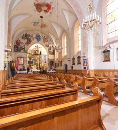 Zdjęcie nr 13: Kościół orientowany, murowany z cegły i kamienia, jednonawowy, na rzucie wydłużonego prostokąta z prezbiterium zamkniętym trójbocznie, wieżą na osi, zakrystią przy północnej ścianie prezbiterium, kruchtą przy południowej ścianie nawy i kaplicą od północy. Nawa pięcioprzęsłowa, ściany gładkie, sklepienie kolebkowe z lunetami, gurt między drugim, a trzecim przęsłem, pięć okien po stronie południowej, po północnej blendy odpowiadające wielkością i kształtem przeciwległym otworom okiennym. Prezbiterium oddzielone ścianą tęczową przeprutą łukiem o kształcie lekko zaostrzonym, dwuprzęsłowe, o sklepieniu krzyżowym, z dwoma ostrołukowymi oknami w ścianie południowej; zakrystia o sklepieniu sieciowym/gwiaździstym. Od zachodu chór wsparty arkadami z łukami o profilu lekko zaostrzonym, z balustradą zdobioną motywem rombu wypełnionego czworoliściem. Pod chórem skarbiec. Wejście główne od zachodu, boczne od południa z kruchtą (w nim kamienny portal z 1673 roku), kolejne od zakrystii, między zakrystią, a prezbiterium gotycki ostrołukowy portal z żelaznymi drzwiami z kratownicą rombową. 
Fasada wieżowa, z wejściem na osi po czterech stopniach. Przedsionek zwieńczony trójkątnym przyczółkiem z zatkniętym na szczycie krzyżem łacińskim. Drzwi zamknięte półkoliście, ponad nimi płaskorzeźba z przedstawieniem głowy Chrystusa otoczonej winną latoroślą. 
Wieża trójkondygnacyjna, zwieńczona trójkątnym przyczółkiem; w dolnej kondygnacji okulus, w środkowej okno zamknięte półkoliście, w ostatniej zegar w niszy powtarzającej kształt okna poniżej. 
Bryła rozczłonkowana; całość budynku obiega cokół, fragmentami kamienny, elewacje boczne oraz prezbiterium wsparte przyporami. Trzy przęsła nawy głównej otynkowane, reszta z cegły. Dachy dwuspadowe, nad pierwszymi dwoma przęsłami nawy niższy niż nad pozostałymi. Nad czwartym przęsłem nawy wieloboczna wieżyczka na sygnaturkę przepruta arkadami, przykryta dachem ostrosłupowym zakończonym kulą z krzyżem łacińskim.  
Do najcenniejszego wyposażenia kościoła należą: ołtarz główny z obrazem Ukrzyżowanego Chrystusa pędzla Jana Triciusa oraz słynący cudami obraz Matki Boskiej w ołtarzu bocznym. 
