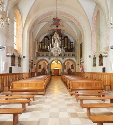 Zdjęcie nr 15: Kościół orientowany, murowany z cegły i kamienia, jednonawowy, na rzucie wydłużonego prostokąta z prezbiterium zamkniętym trójbocznie, wieżą na osi, zakrystią przy północnej ścianie prezbiterium, kruchtą przy południowej ścianie nawy i kaplicą od północy. Nawa pięcioprzęsłowa, ściany gładkie, sklepienie kolebkowe z lunetami, gurt między drugim, a trzecim przęsłem, pięć okien po stronie południowej, po północnej blendy odpowiadające wielkością i kształtem przeciwległym otworom okiennym. Prezbiterium oddzielone ścianą tęczową przeprutą łukiem o kształcie lekko zaostrzonym, dwuprzęsłowe, o sklepieniu krzyżowym, z dwoma ostrołukowymi oknami w ścianie południowej; zakrystia o sklepieniu sieciowym/gwiaździstym. Od zachodu chór wsparty arkadami z łukami o profilu lekko zaostrzonym, z balustradą zdobioną motywem rombu wypełnionego czworoliściem. Pod chórem skarbiec. Wejście główne od zachodu, boczne od południa z kruchtą (w nim kamienny portal z 1673 roku), kolejne od zakrystii, między zakrystią, a prezbiterium gotycki ostrołukowy portal z żelaznymi drzwiami z kratownicą rombową. 
Fasada wieżowa, z wejściem na osi po czterech stopniach. Przedsionek zwieńczony trójkątnym przyczółkiem z zatkniętym na szczycie krzyżem łacińskim. Drzwi zamknięte półkoliście, ponad nimi płaskorzeźba z przedstawieniem głowy Chrystusa otoczonej winną latoroślą. 
Wieża trójkondygnacyjna, zwieńczona trójkątnym przyczółkiem; w dolnej kondygnacji okulus, w środkowej okno zamknięte półkoliście, w ostatniej zegar w niszy powtarzającej kształt okna poniżej. 
Bryła rozczłonkowana; całość budynku obiega cokół, fragmentami kamienny, elewacje boczne oraz prezbiterium wsparte przyporami. Trzy przęsła nawy głównej otynkowane, reszta z cegły. Dachy dwuspadowe, nad pierwszymi dwoma przęsłami nawy niższy niż nad pozostałymi. Nad czwartym przęsłem nawy wieloboczna wieżyczka na sygnaturkę przepruta arkadami, przykryta dachem ostrosłupowym zakończonym kulą z krzyżem łacińskim.  
Do najcenniejszego wyposażenia kościoła należą: ołtarz główny z obrazem Ukrzyżowanego Chrystusa pędzla Jana Triciusa oraz słynący cudami obraz Matki Boskiej w ołtarzu bocznym. 
