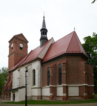 Zdjęcie nr 1: Kościół orientowany, murowany z cegły i kamienia, jednonawowy, na rzucie wydłużonego prostokąta z prezbiterium zamkniętym trójbocznie, wieżą na osi, zakrystią przy północnej ścianie prezbiterium, kruchtą przy południowej ścianie nawy i kaplicą od północy. Nawa pięcioprzęsłowa, ściany gładkie, sklepienie kolebkowe z lunetami, gurt między drugim, a trzecim przęsłem, pięć okien po stronie południowej, po północnej blendy odpowiadające wielkością i kształtem przeciwległym otworom okiennym. Prezbiterium oddzielone ścianą tęczową przeprutą łukiem o kształcie lekko zaostrzonym, dwuprzęsłowe, o sklepieniu krzyżowym, z dwoma ostrołukowymi oknami w ścianie południowej; zakrystia o sklepieniu sieciowym/gwiaździstym. Od zachodu chór wsparty arkadami z łukami o profilu lekko zaostrzonym, z balustradą zdobioną motywem rombu wypełnionego czworoliściem. Pod chórem skarbiec. Wejście główne od zachodu, boczne od południa z kruchtą (w nim kamienny portal z 1673 roku), kolejne od zakrystii, między zakrystią, a prezbiterium gotycki ostrołukowy portal z żelaznymi drzwiami z kratownicą rombową. 
Fasada wieżowa, z wejściem na osi po czterech stopniach. Przedsionek zwieńczony trójkątnym przyczółkiem z zatkniętym na szczycie krzyżem łacińskim. Drzwi zamknięte półkoliście, ponad nimi płaskorzeźba z przedstawieniem głowy Chrystusa otoczonej winną latoroślą. 
Wieża trójkondygnacyjna, zwieńczona trójkątnym przyczółkiem; w dolnej kondygnacji okulus, w środkowej okno zamknięte półkoliście, w ostatniej zegar w niszy powtarzającej kształt okna poniżej. 
Bryła rozczłonkowana; całość budynku obiega cokół, fragmentami kamienny, elewacje boczne oraz prezbiterium wsparte przyporami. Trzy przęsła nawy głównej otynkowane, reszta z cegły. Dachy dwuspadowe, nad pierwszymi dwoma przęsłami nawy niższy niż nad pozostałymi. Nad czwartym przęsłem nawy wieloboczna wieżyczka na sygnaturkę przepruta arkadami, przykryta dachem ostrosłupowym zakończonym kulą z krzyżem łacińskim.  
Do najcenniejszego wyposażenia kościoła należą: ołtarz główny z obrazem Ukrzyżowanego Chrystusa pędzla Jana Triciusa oraz słynący cudami obraz Matki Boskiej w ołtarzu bocznym. 
