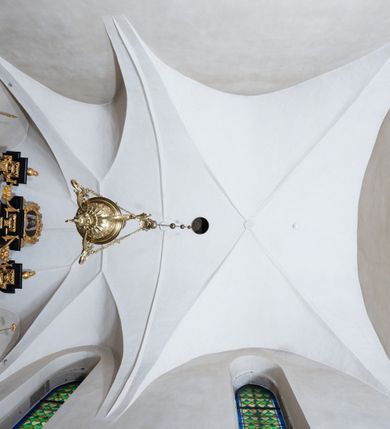 Zdjęcie nr 4: Kościół orientowany, murowany z cegły i kamienia, jednonawowy, na rzucie wydłużonego prostokąta z prezbiterium zamkniętym trójbocznie, wieżą na osi, zakrystią przy północnej ścianie prezbiterium, kruchtą przy południowej ścianie nawy i kaplicą od północy. Nawa pięcioprzęsłowa, ściany gładkie, sklepienie kolebkowe z lunetami, gurt między drugim, a trzecim przęsłem, pięć okien po stronie południowej, po północnej blendy odpowiadające wielkością i kształtem przeciwległym otworom okiennym. Prezbiterium oddzielone ścianą tęczową przeprutą łukiem o kształcie lekko zaostrzonym, dwuprzęsłowe, o sklepieniu krzyżowym, z dwoma ostrołukowymi oknami w ścianie południowej; zakrystia o sklepieniu sieciowym/gwiaździstym. Od zachodu chór wsparty arkadami z łukami o profilu lekko zaostrzonym, z balustradą zdobioną motywem rombu wypełnionego czworoliściem. Pod chórem skarbiec. Wejście główne od zachodu, boczne od południa z kruchtą (w nim kamienny portal z 1673 roku), kolejne od zakrystii, między zakrystią, a prezbiterium gotycki ostrołukowy portal z żelaznymi drzwiami z kratownicą rombową. 
Fasada wieżowa, z wejściem na osi po czterech stopniach. Przedsionek zwieńczony trójkątnym przyczółkiem z zatkniętym na szczycie krzyżem łacińskim. Drzwi zamknięte półkoliście, ponad nimi płaskorzeźba z przedstawieniem głowy Chrystusa otoczonej winną latoroślą. 
Wieża trójkondygnacyjna, zwieńczona trójkątnym przyczółkiem; w dolnej kondygnacji okulus, w środkowej okno zamknięte półkoliście, w ostatniej zegar w niszy powtarzającej kształt okna poniżej. 
Bryła rozczłonkowana; całość budynku obiega cokół, fragmentami kamienny, elewacje boczne oraz prezbiterium wsparte przyporami. Trzy przęsła nawy głównej otynkowane, reszta z cegły. Dachy dwuspadowe, nad pierwszymi dwoma przęsłami nawy niższy niż nad pozostałymi. Nad czwartym przęsłem nawy wieloboczna wieżyczka na sygnaturkę przepruta arkadami, przykryta dachem ostrosłupowym zakończonym kulą z krzyżem łacińskim.  
Do najcenniejszego wyposażenia kościoła należą: ołtarz główny z obrazem Ukrzyżowanego Chrystusa pędzla Jana Triciusa oraz słynący cudami obraz Matki Boskiej w ołtarzu bocznym. 
