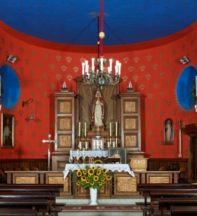 Zdjęcie nr 8: Kościół Najświętszej Marii Panny Królowej jest zlokalizowany w centrum Będkowic, na zachód od głównej drogi. Teren przykościelny jest otoczony wysokim murem posadowionym na kamiennej podmurówce oraz słupkach z nieregularnych ciosów kamienia i z żeliwnym płotem. W części wschodniej muru zlokalizowana jest szeroka brama, do której prowadzą schody, druga brama usytuowana jest nieco z prawej strony, również od wschodu.

Kościół jest skierowany na zachód, murowany, jednonawowy na rzucie prostokąta z prezbiterium zamkniętym półkoliście. Wnętrze tworzy szeroka nawa nakryta stropem oraz węższe i krótkie prezbiterium. Od północy przylega niewielka zakrystia na planie prostokąta z oknem od południa. Wejście do zakrystii zaznaczone jest drewnianym portalem. Na wschodniej ścianie nawy chór muzyczny, wsparty na dwóch słupach, dostępny klatką schodową od nawy. 

Nawę oświetlają dwa duże, rozglifione, prostokątne i zamknięte półkoliście okna umieszczone w południowej oraz północnej ścianie, a także dwa mniejsze okna ulokowane pod chórem zamknięte łukami odcinkowymi. Po bokach prezbiterium są dwa okrągłe okna. Wszystkie otwory okienne w nawie i prezbiterium wypełnione są witrażami lub ozdobnymi przeszkleniami. Do kościoła prowadzi główne wejście od strony wschodniej oraz jedno mniejsze od zakrystii.

Wygląd zewnętrznej elewacji kościoła jest skromny. Prezbiterium niższe od nawy, nad środkiem nawy wznosi się wieżyczka na sygnaturkę z latarnią, nakryta iglicą. Fasada prosta, w dolnej części wejście główne do świątyni, prostokątne, zamknięte łukiem półkolistym, powyżej okrągłe okno, a po bokach dwa mniejsze, prostokątne, zamknięte łukiem odcinkowym. W zwieńczeniu prostokątna, przeszklona, zamknięte półkoliście wnęka z figurą Chrystusa Frasobliwego, a na szczycie prosta aedikula z prześwitem, w której zawieszony jest mały dzwon. U góry łaciński krzyż na cokole. Otwory okienne i drzwiowe zdobione są kamienną okładziną. Świątynia nakryta jest dachem dwuspadowym.

