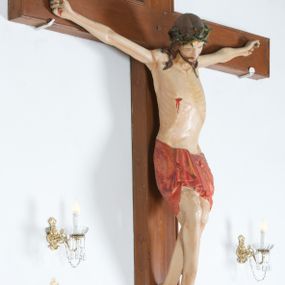 Zdjęcie nr 1: Do krzyża przybita trzema gwoździami figura Chrystusa na szeroko rozpiętych ramionach, z nogami ugiętymi w kolanach, założonymi prawa na lewą. Chrystus został przedstawiony w typie Cristo vivo, ze spuszczoną na prawe ramię głową, z otwartymi oczami. Spod zielonej korony cierniowej spływają na ramiona i plecy ciemnobrązowe, długie włosy. Biodra ciasno okryte czerwonym perizonium przewiązanym na prawym boku, z końcem układającym się w drobne, kaskadowe fałdy. Sylwetka szczupła o podkreślonej linii żeber; na ciele widoczne ślady Męki. Nad głową Chrystusa titulus w formie banderoli z napisem: „INRI”. Krzyż gładki, brązowy; polichromia w odsłoniętych partiach ciała naturalistyczna.  