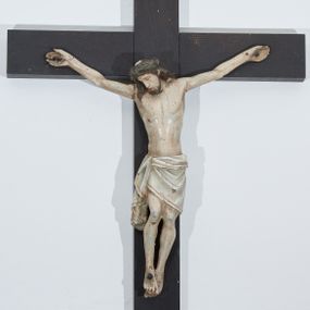 Zdjęcie nr 1: Chrystus przybity do krzyża trzema gwoździami. Figura w delikatnym zwisie, ramiona szeroko rozłożone, kolana silnie ugięte, stopy w układzie prawa na lewą. Twarz podłużna o długim nosie, oczy i usta zamknięte; okolona krótką brodą zakończoną dwoma puklami. Włosy długie, ciemnobrązowe, opadające na plecy i prawe ramię. Na głowie ciemnozielona korona cierniowa. Sylwetka szczupła z wyraźnie uwypukloną linią żeber klatki piersiowej i wąską talią. Ciało pokrywają liczne strużki krwi. Perizonium w formie tkaniny ściśle owijającej biodra, zawiązanej na prawym boku ze zwisem wzdłuż prawego uda. Nad głową Chrystusa biały, pionowy titulus w formie banderoli z napisem: „I(ESUS) N(AZARENUS) / R(EX) I(UDAEROUM)”. Krzyż gładki, malowany na kolor ciemnobrązowy. Polichromia naturalistyczna w odsłoniętych partiach ciała, perizonium białe ze złotą lamówką.