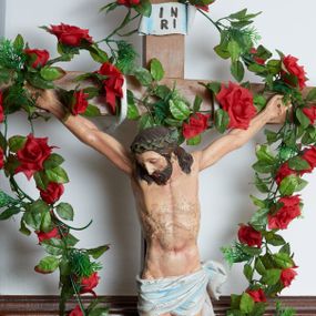 Zdjęcie nr 1: Chrystus przybity do krzyża trzema gwoździami. Figura w silnym zwisie, ramiona szeroko rozłożone, kolana delikatnie ugięte, stopy w układzie prawa na lewą. Twarz podłużna, szczupła, o długim nosie, oczy i usta zamknięte; okolona krótką brodą zakończoną dwoma puklami. Włosy średniej długości, ułożone w skręcone pukle opadające na kark i ramiona. Na głowie zielona korona cierniowa. Sylwetka szczupła z wyraźnie uwypuklonym umięśnieniem i linią żeber klatki piersiowej. Perizonium w formie tkaniny ściśle owijającej biodra, zawiązanej na lewym boku ze zwisem wzdłuż lewego uda. Nad głową Chrystusa biały titulus w formie banderoli z napisem: „I(ESUS) N(AZARENUS) / R(EX) I(UDAEROUM)”. Krzyż gładki o trójlistnie zakończonych ramionach, malowany na kolor jasnobrązowy. Polichromia naturalistyczna w odsłoniętych partiach ciała, perizonium białe z błękitnym cieniowaniem.