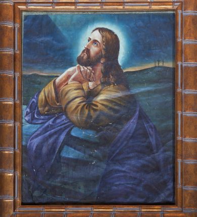 Zdjęcie nr 1: Obraz w kształcie stojącego prostokąta przedstawia Modlitwę w Ogrójcu. Chrystus ukazany jest w pozycji klęczącej, zwrócony w swoją prawą stronę ze splecionymi dłońmi, którymi podpiera podbródek. Twarz ujęta z lewego profilu, podłużna z dużymi oczami i długim nosem, okolona ciemną brodą. Pasma włosów spływają na lewe ramię i plecy, a głowę otacza świetlisty nimb. Chrystus ubrany jest w jasnobrązową suknię i ciemnoniebieski płaszcz. W tle po prawej stronie widok na Golgotę z trzema krzyżami. Kolorystyka ciemna z przewagą koloru ciemnoniebieskiego i ciemnej zieleni. 