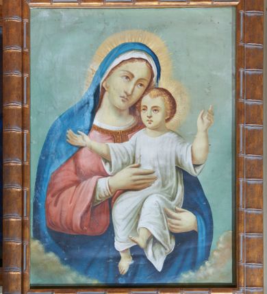 Zdjęcie nr 1: Obraz w kształcie stojącego prostokąta z przedstawieniem Matki Boskiej z Dzieciątkiem. W centrum kompozycji ukazana Matka Boska w półpostaci, frontalnie z głową delikatnie przechyloną w lewo. Na lewej ręce trzyma Dzieciątko Jezus. Maria ma owalną twarz o delikatnych rysach z długim nosem, okoloną brązowymi włosami, schowanymi pod welonem. Ubrana jest w białą szatę spodnią z długimi i wąskimi rękawami oraz czerwoną suknię z długimi i szerokimi rękawami, obszytą przy dekolcie złotą bordiurą. Ponadto na głowie ma biały welon i niebieski płaszcz otulający całą postać. Dzieciątko siedzi, zwrócone trzy czwarte w prawo z szeroko rozłożonymi na boki rękami. Twarz o dziecięcych rysach, włosy jasne i kędzierzawe. Jest ubrane w białą długą sukienkę; stopy bose. Postacie zostały ukazane na tle jasnobłękitnego nieba i obłoków skumulowanych w dolnej partii obrazu. Kolorystyka obrazu stonowana, jasna.