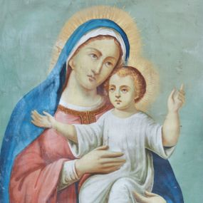 Zdjęcie nr 1: Obraz w kształcie stojącego prostokąta z przedstawieniem Matki Boskiej z Dzieciątkiem. W centrum kompozycji ukazana Matka Boska w półpostaci, frontalnie z głową delikatnie przechyloną w lewo. Na lewej ręce trzyma Dzieciątko Jezus. Maria ma owalną twarz o delikatnych rysach z długim nosem, okoloną brązowymi włosami, schowanymi pod welonem. Ubrana jest w białą szatę spodnią z długimi i wąskimi rękawami oraz czerwoną suknię z długimi i szerokimi rękawami, obszytą przy dekolcie złotą bordiurą. Ponadto na głowie ma biały welon i niebieski płaszcz otulający całą postać. Dzieciątko siedzi, zwrócone trzy czwarte w prawo z szeroko rozłożonymi na boki rękami. Twarz o dziecięcych rysach, włosy jasne i kędzierzawe. Jest ubrane w białą długą sukienkę; stopy bose. Postacie zostały ukazane na tle jasnobłękitnego nieba i obłoków skumulowanych w dolnej partii obrazu. Kolorystyka obrazu stonowana, jasna.