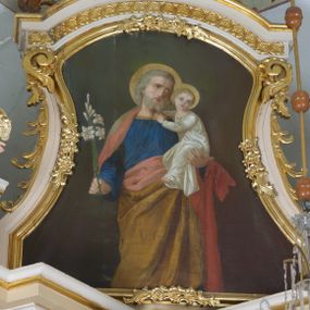 Zdjęcie nr 1: Obraz w kształcie stojącego prostokąta o wklęsło-wypukłych bokach. W centrum kompozycji św. Józef ukazany frontalnie, do wysokości kolan, z Dzieciątkiem Jezus na lewej ręce i gałązką białej lilii w prawej, z głową delikatnie zwróconą w lewo. Święty ubrany jest w błękitną suknię z długimi rękawami, obszytą złotą lamówką oraz jasnobrązowy płaszcz z różową podszewką, założony na plecy i spływający pod prawą ręką na lewe ramię. Twarz owalna, okolona średniej długości, siwą brodą, wzrok skierowany do góry, włosy siwe, zasłaniające uszy. Dzieciątko ukazane w pozycji siedzącej, zwrócone trzy czwarte w prawo, z głową skierowaną na wprost, rękami obejmujące za szyję św. Józefa. Ubrane w długą, białą sukienkę z długimi rękawami. Dłonie św. Józefa i Dzieciątka smukłe, o długich i subtelnych palcach. Wokół głów św. Józefa i Dzieciątka złote, koliste nimby. Tło obrazu jednolite i ciemnozielone.