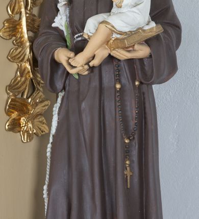 Zdjęcie nr 1: Rzeźba ustawiona na wysokim prostopadłościennym cokole, o ściętych narożach, w górnej części profilowanym. Święty ukazany frontalnie, w postawie stojącej, z Dzieciątkiem Jezus na lewym ręku i gałązką białej lilii w prawej dłoni, z głową delikatnie zwróconą w stronę Dzieciątka. Święty ubrany w habit franciszkański, przewiązany sznurem na prawym boku, z różańcem zwisającym po lewej stronie, z tonsurą na głowie. Twarz trójkątna, z długim i szerokim nosem, wzrokiem skierowanym na Dzieciątko; policzki zarumienione. Dzieciątko ukazane w pozycji siedzącej na otwartej księdze, widoczne z lewego profilu, z rękami wzniesionymi do góry i z głową uniesioną w stronę św. Antoniego. Ubrane w białą sukienkę do kolan, z rękawami podwiniętymi do łokci, na brzegach obwiedzioną złotą lamówką. 

Polichromia w odsłoniętych partiach ciała naturalistyczna.