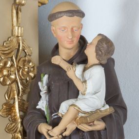 Zdjęcie nr 1: Rzeźba ustawiona na wysokim prostopadłościennym cokole, o ściętych narożach, w górnej części profilowanym. Święty ukazany frontalnie, w postawie stojącej, z Dzieciątkiem Jezus na lewym ręku i gałązką białej lilii w prawej dłoni, z głową delikatnie zwróconą w stronę Dzieciątka. Święty ubrany w habit franciszkański, przewiązany sznurem na prawym boku, z różańcem zwisającym po lewej stronie, z tonsurą na głowie. Twarz trójkątna, z długim i szerokim nosem, wzrokiem skierowanym na Dzieciątko; policzki zarumienione. Dzieciątko ukazane w pozycji siedzącej na otwartej księdze, widoczne z lewego profilu, z rękami wzniesionymi do góry i z głową uniesioną w stronę św. Antoniego. Ubrane w białą sukienkę do kolan, z rękawami podwiniętymi do łokci, na brzegach obwiedzioną złotą lamówką. 

Polichromia w odsłoniętych partiach ciała naturalistyczna.