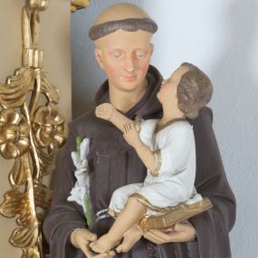 Zdjęcie nr 1: Rzeźba ustawiona na wysokim prostopadłościennym cokole, o ściętych narożach, w górnej części profilowanym. Święty ukazany frontalnie, w postawie stojącej, z Dzieciątkiem Jezus na lewym ręku i gałązką białej lilii w prawej dłoni, z głową delikatnie zwróconą w stronę Dzieciątka. Święty ubrany w habit franciszkański, przewiązany sznurem na prawym boku, z różańcem zwisającym po lewej stronie, z tonsurą na głowie. Twarz trójkątna, z długim i szerokim nosem, wzrokiem skierowanym na Dzieciątko; policzki zarumienione. Dzieciątko ukazane w pozycji siedzącej na otwartej księdze, widoczne z lewego profilu, z rękami wzniesionymi do góry i z głową uniesioną w stronę św. Antoniego. Ubrane w białą sukienkę do kolan, z rękawami podwiniętymi do łokci, na brzegach obwiedzioną złotą lamówką. 

Polichromia w odsłoniętych partiach ciała naturalistyczna.