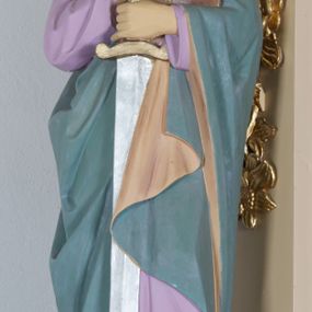 Zdjęcie nr 1: Rzeźba ustawiona na niskim prostopadłościennym postumencie o ściętych narożach. Święty Paweł ukazany w postawie stojącej, frontalnie, w delikatnym kontrapoście, z księgą w prawej dłoni i mieczem katowskim, zwróconym ostrzem w dół w dłoni lewej. Ubrany w jasnofioletową, długą suknię z długimi rękawami oraz zielony płaszcz z jasnobrązową podszewką, założony na lewe ramię i spływający pod prawą ręką do przodu. Twarz owalna z długim i wąskim nosem, małymi oczami i ustami; okolona długą, ciemnobrązową brodą, ułożoną w dwa, długie pukle oraz średniej długości włosami, zasłaniającymi uszy.  Polichromia w odsłoniętych partiach ciała naturalistyczna, rękojeść miecza złocona, ostrze srebrzone.
