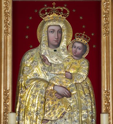 Zdjęcie nr 2: Obraz w kształcie stojącego prostokąta z przedstawianiem Matki Boskiej Śnieżnej. Maria ukazana frontalnie, w półpostaci, z Dzieciątkiem Jezus na lewym ręku, z chustką w skrzyżowanych dłoniach. Twarz podłużna, z długim i wąskim nosem, drobnymi ustami, dużymi oczami podkreślonymi regularnymi łukami brwiowymi. Dzieciątko zwrócone trzy czwarte w prawo, w pozycji siedzącej, z zamkniętą księgą w lewej dłoni, prawą czyniące gest błogosławieństwa. Twarz okrągła o wyrazistych rysach; duże, niebieskie oczy, zarumienione policzki; włosy krótkie, kręcone i jasne. Tło przedstawienia wypełnione czerwonym pluszem. Na postacie Marii i Dzieciątka nałożona metalowa sukienka, trybowana w motywy kwiatowo-liściaste oraz koliste nimby. Na głowach Marii i Jezusa korony zamknięte, zdobione kamieniami i zwieńczone krzyżykami, a wokół koliste nimby i wieniec z 12 gwiazd. 

