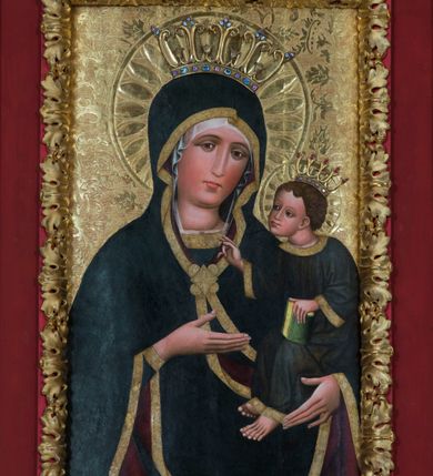 Zdjęcie nr 2: Obraz w kształcie stojącego prostokąta z półpostaciowym przedstawieniem Madonny podtrzymującej lewą ręką Dzieciątko Jezus. Maria ukazana jest na wprost, lekko przechyloną w lewo głowę charakteryzuje owalna, pociągła twarz o wyrazistych oczach z nieznacznie przymkniętymi powiekami, długim, prostym nosie, niewielkich ustach o opadających kącikach, wyraźnie zaróżowionych policzkach oraz subtelnie zaznaczonym podbródku. Maria ubrana jest w ciemnogranatową suknię z szerokimi, dekoracyjnymi, złoconymi obszyciami dekoltu i wąskich mankietów. Na jej głowie jest biała, półprzejrzysta chusta widoczna spod osłaniającego całą sylwetkę ciemnogranatowego płaszcza o bordowej podszewce i szerokiej, złoconej, dekoracyjnej lamówce, spiętego na piersiach dużą, złoconą broszą w kształcie rombu z czterema kółkami przylegającymi do jego lekko wklęsłych boków. Prawą ręką o smukłej, wyprostowanej dłoni Maria wskazuje na trzymane na lewej ręce siedzące Dzieciątko. Zwrócony w trzech czwartych w prawo Jezus lekko pochyla się do przodu. Pociągłą, o trójkątnym obrysie szczęki twarz charakteryzują duże, wyraziste oczy o nieznacznie przymkniętych powiekach, długi, prosty nos oraz niewielkie usta. Krótkie, brązowe, skręcone włosy opadają parą pukli na czoło Dzieciątka. Ubrane jest ono w długą, ciemnogranatową suknię z szerokimi, dekoracyjnymi, złoconymi lamówkami, spod której widoczne są bose stopy. Jezus prawą dłoń unosi w geście błogosławieństwa, lewą trzyma wspartą na kolanach zamkniętą księgę w zielonej oprawie. Głowy postaci okalają ryte w gruncie podobrazia nimby z motywami eliptycznych promieni ujętych wąskim okręgiem, dodatkowo wieńczą je złocone, kameryzowane korony otwarte. Złocone tło przedstawienia zdobi grawerowana wić roślinna. Obraz ujęty jest złoconą ramą w formie ażurowego układu liści akantu.      