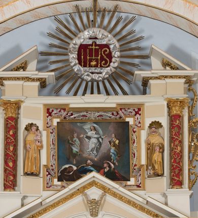 Zdjęcie nr 2: Obraz w kształcie leżącego prostokąta zawiera przedstawienie sceny Przemienienia Jezusa na Górze Tabor. Kompozycję malowidła charakteryzuje dwustrefowość. W górnej partii, na tle ciemnobłękitnego nieba i szaro-różowych obłoków ukazane są trzy, unoszące się postaci. Pośrodku znajduje się sylwetka wyobrażonego na wprost Jezusa w zdynamizowanej pozie. Zwróconą w trzech czwartych w prawo głowę charakteryzuje owalna twarz o wyrazistych rysach, zaróżowionych policzkach oraz krótkim, brązowym zaroście. Długie, falowane włosy opadają na plecy. Jezus ubrany jest w długą, białą, przewiązaną w pasie suknię oraz przerzucony przez ramiona, mocno rozwiany, unoszący się ponad jego głową, biały płaszcz. Ręce rozłożone są na boki, natomiast prawa noga zgięta jest w kolanie. Po lewej stronie Jezusa znajduje się ukazany niemal na wprost Mojżesz. Zwróconą w trzech czwartych w lewo głowę charakteryzuje zaokrąglona twarz o wyrazistych rysach dojrzałego mężczyzny z dużymi oczami, wydatnym nosem, bruzdami na czole oraz krótkim, siwym zarostem. Długie, zaczesane do tyłu włosy opadają na plecy mężczyzny. Strój Mojżesza stanowi długa, zielona suknia oraz narzucony na lewą rękę i osłaniający znacznie jego sylwetkę jasnozielony płaszcz z odcieniami szarości. Lewa noga jest zgięta w kolanie. Mężczyzna oburącz podtrzymuje parę prostokątnych, półkoliście zakończonych tablic kamiennych z wypisanymi na nich rzymskimi numerami. Ponad głową Mojżesza widnieje para wiązek promieni. Po prawej stronie Jezusa znajduje się sylwetka zwróconego w trzech czwartych w prawo Eliasza. Ukazaną w profilu twarz charakteryzują wyraziste rysy dojrzałego mężczyzny o dużych oczach i nosie oraz z krótkim, siwym zarostem. Krótkie włosy odsłaniają duże ucho. Mężczyzna ubrany jest w długą, błękitną suknię oraz przerzucony przez lewą rękę jasnobrązowy płaszcz. W prawej ręce trzyma zamkniętą księgę, lewą unosi na wysokości klatki piersiowej. Lewa noga jest zgięta w kolanie. W dolnej partii obrazu ukazane są półpostaciowo sylwetki trzech apostołów usytuowanych na tle łagodnego wzniesienia. Po prawej stronie kompozycji znajduje się zwrócony w trzech czwartych w prawo św. Jan. Jego młodzieńczą, pozbawioną zarostu i ukazaną w profilu twarz charakteryzują wyraziste rysy z półprzymkniętymi oczami, zadartym nosem, pełnymi ustami oraz wydatnymi kośćmi policzkowymi i zarysem szczęki. Długie, ciemnobrązowe włosy opadają na plecy. Apostoł ubrany jest w ciemnozieloną suknię z podciągniętym rękawem oraz przerzucony przez prawe ramię czerwony płaszcz. Prawą rękę wspiera na piersiach, lewą wzniesioną, przesłania oczy. Pośrodku znajduje się ukazany tyłem św. Piotr. Zwróconą profilem w prawo i odchyloną mocno do tyłu głowę charakteryzuje twarz o rysach mężczyzny w podeszłym wieku z długim, prostym nosem i krótkim, siwym zarostem. Wydatną łysinę ujmuje pas krótkich, siwych włosów u nasady głowy oraz kępa tuż nad czołem. Święty ubrany jest w niebieską suknię oraz okalający sylwetkę brązowy płaszcz. Po lewej stronie kompozycji ukazany jest zwrócony na wprost, nieco pochylony św. Jakub Starszy. Twarz o rysach dojrzałego mężczyzny charakteryzuje śniada karnacja, długi, zaokrąglony na końcu nos oraz długi, ciemnobrązowy zarost. Święty ubrany jest w ciemnobrązową suknię oraz okalający sylwetkę ciemnobrązowy płaszcz z kremową podszewką. Sylwetki postaci charakteryzują zdynamizowane pozy, a ich szaty są intensywnie drapowane i rozwiane. 
Modelunek cechuje dynamicznie kształtowana plama barwna o intensywnej, zróżnicowanej i nasyconej kolorystyce oraz kontrastowych zestawieniach.      
