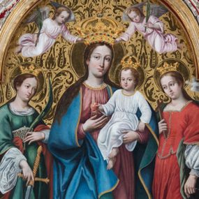 Zdjęcie nr 1: Obraz w kształcie stojącego prostokąta zamkniętego półkolistym łukiem nadwieszonym przedstawia całopostaciowy wizerunek Madonny z Dzieciątkiem w otoczeniu św. Małgorzaty i św. Katarzyny Aleksandryjskiej. Stojąca w wydatnym kontrapoście Maria nieznacznie zwrócona jest w trzech czwartych w lewo. Długie, falowane, jasnobrązowe włosy opadają na ramiona i plecy. Maria ubrana jest w jasnoczerwoną, spiętą w pasie suknię z lamowanym wykończeniem dekoltu z koronką oraz narzucony na ramiona, podwinięty pod prawą rękę i osłaniający prawą nogę niebieski płaszcz ze złoconym obszyciem. Pod jej stopami znajduje się sierp księżyca. Prawą dłonią wskazuje na podtrzymywane lewą ręką Dzieciątko Jezus w trzech czwartych zwrócone w prawo. Subtelną, o dziecięcych rysach twarz ujmują krótkie, kręcone włosy z pojedynczym puklem nad czołem. Jezus ubrany jest w długą, białą suknię, przewiązaną w pasie i z podobnym do sukni Marii wykończeiem dekoltu. W prawej, nieznacznie uniesionej ręce trzyma jabłko, lewą, lekko zgiętą w łokciu, opuszcza wzdłuż ciała. Po prawej stronie Madonny stoi w kontrapoście, zwrócona w trzech czwartych w prawo św. Małgorzata. Długie, jasnobrązowe włosy opadają na plecy. Święta ubrana jest w długą, czerwoną suknię częściowo obszytą perłami, z odciętym gorsetem o kwadratowym dekolcie i krótkich, szerokich rękawach, spod których widoczna jest biała koszula o obszernych, bufiastych rękawach i wąskich mankietach. Plecy osłania długi, zielony płaszcz, którego poła wsunięta jest pod lewą, opuszczoną wzdłuż ciała ręką. W prawej, wspartej na piersiach święta trzyma niewielki krzyż. Pod jej stopami znajduje się sylwetka spoglądającego do góry smoka z obrożą na szyi, której łańcuch święta trzyma w lewej dłoni. Tuż nad lewym ramieniem św. Małgorzaty unosi się biały gołąb. Po lewej stronie Madonny stoi w kontrapoście św. Katarzyna Aleksandryjska zwrócona w trzech czwartych lewo. Zaczesane do tyłu długie włosy opadają na plecy. Święta ubrana jest w jasnofioletową spódnicę i białą koszulę której obszerny kołnierz i szeroki rękaw z wąskim mankietem widoczne są spod sięgającej kolan, zielonej sukni o podsuniętych, szerokich rękawach i bogato kameryzowanym gorsecie. Rękami podtrzymuje zsuwający się z pleców czerwony płaszcz. W lewej, uniesionej na wysokości talii ręce trzyma gałązkę palmową, prawą, opuszczoną w dół podtrzymuje wsparty na podłożu miecz. U stóp świętej leży fragment złamanego koła. Owalne twarze Marii i świętych charakteryzuje jasna karnacja, delikatny modelunek, subtelne, młodzieńcze rysy oraz lekko zaróżowione policzki. Głowę Madonny i Dzieciątka wieńczą zamknięte korony, a świętych – korony w typie otwartym; wszystkie są kameryzowane. W górnej partii przedstawienia unosi się para ubranych w jasnoróżowe sukienki aniołów nakładających koronę na głowę Marii i  trzymających w dłoniach gałązki palmowe. Tło przedstawienia jest złocone z rytą dekoracją w formie ornamentyki roślinnej, głowy świętych, Marii i Dzieciątka okalają nimby, natomiast u góry kompozycji widoczny jest fragment tarczy słonecznej.      