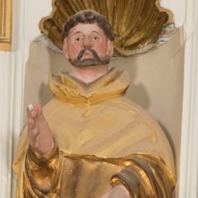 Zdjęcie nr 1: Całopostaciowa, drążona z tyłu figura św. Dominika stojącego w układzie frontalnym, w kontrapoście, na niewielkim, prostopadłościennym postumencie. Kwadratową w obrysie twarz cechują sumarycznie opracowane rysy z wydatnym nosem, niewielkimi, szeroko rozstawionymi oczami oraz podkreślonymi rumieńcem policzkami i czubkiem nosa oraz krótkim zarostem. Krótko przystrzyżone, skręcone włosy z wygoloną tonsurą odsłaniają duże, przylegające do głowy uszy. Święty ubrany jest w złocony habit dominikański ze szkaplerzem i kukullą, której połę podtrzymuje lewą ręką, prawą unosi w geście błogosławieństwa. Dłonie świętego są duże i szerokie o sumarycznym modelunku placów. U stóp świętego, po lewej stronie znajduje się srebrzona sylwetka leżącego psa.     