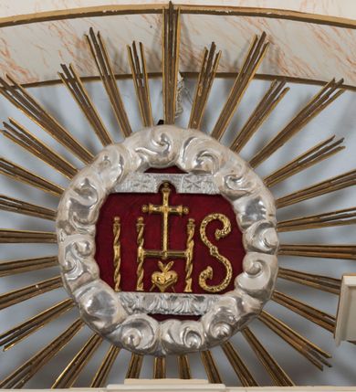 Zdjęcie nr 3: Ołtarz architektoniczny, dwukondygnacyjny, trójosiowy, ze zwieńczeniem. Ołtarz murowany, prostopadłościenny z marmurowym antepedium. Tabernakulum w formie prostopadłościennej, metalowej szafki ujętej parą ażurowych spływów wolutowych w formie stylizowanych wici akantowych. Drzwiczki, w kształcie zbliżonym do kwadratu, zdobione motywem krzyża i banderoli z napisem „IHS” ujętych kłosami zboża i kiściami winnej latorośli. Tron wystawienia w formie baldachimu wspartego na 4 kolumienkach. Krawędź zwieńczenia ujęta jest ornamentyką roślinną, w motywem kartusza z krzyżem po środku. Oś środkowa retabulum osadzona na wysokim, zdwojonym cokole o zryzalitowanych bokach. Pierwszą kondygnację ujmują dwie pary kolumn o kanelowanych trzonach i korynckich kapitelach, z czego wewnętrzne wysunięte względem lica nastawy, wspierających wyłamujące się ponad nimi belkowanie, w partii architrawu przybierające kształt  półkolistego łuku nadwieszonego; całość wieńczy forma trójkątnego przyczółka. Druga kondygnacja ujęta parą osadzonych na cokołach kolumn o trzonach zdobionych wicią winnej latorośli, wspierających delikatnie wyłamujące się ponad nimi belkowanie przerwane w partii fryzu u gzymsu. Zwieńczenie w formie trójkątnego, przerwanego przyczółka. W strefie zryzalitowanych po bokach cokołów osi bocznych para półkoliście zamkniętych bramek. Krawędzie zewnętrzne kondygnacji osi bocznych ujęte pojedynczymi kolumnami dźwigającymi wyłamujące się ponad nimi belkowanie wieńczące, będące przedłużeniem belkowania osi środkowej.  Pola cokołu retabulum wypełnione motywami ornamentyki roślinnej, w partii fryzu motywy małżowinowo-chrząstkowe. Druga kondygnacja osi środkowej ujęta parą ażurowych, małżowinowo-chrząstkowych uszaków, szczyt zwieńczenia w formie promienistej glorii z owalnym medalionem ujętym wieńcem obłoków, z monogramem imienia Jezus. Pola osi bocznych w dolnej partii zdobione motywami małżowinowo-chrząstkowego kartusza, w górnej owocowo-kwiatowymi festonami. Skrajne pola cokołu retabulum wypełnia para wizerunków – św. Pawła po prawej stronie i św. Piotra po lewej. Pole pierwszej kondygnacji osi środkowej ma formę płytkiej wnęki w kształcie stojącego prostokąta zamkniętego półkolistym łukiem nadwieszonym, ujętej bogato rzeźbioną ramą z motywem ornamentu małżowinowo-chrząstkowego, w środku obraz Matki Boskiej z Dzieciątkiem. Pole drugiej kondygnacji wypełnia obraz w kształcie leżącego prostokąta, ujęty szeroką ramą z uszakami w narożach, zdobioną ornamentem małżowinowo-chrząstkowym. Po bokach para półkoliście zamkniętych niszy z motywem konchy, wypełnionych parą figur – po prawej stronie św. Dominika, po lewej św. Antoni (?). Pola osi bocznych artykułuje para zamkniętych półkoliście niszy z motywami konchy, z parą rzeźb – św. Stanisława po prawej stronie i św. Wojciecha po lewej.  W szczycie osi bocznych pośrodku para rzeźb flankujących zwieńczenie ołtarza – po prawej stronie św. Wacława, po lewej św. Kazimierza, na końcach para figur aniołów. Struktura polichromowana w odcieniach koloru kremowego i beżowego, detal architektoniczny i ornamentyka złocone i srebrzone.