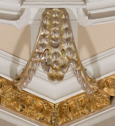 Zdjęcie nr 21: Ołtarz architektoniczny, dwukondygnacyjny, trójosiowy, ze zwieńczeniem. Ołtarz murowany, prostopadłościenny z marmurowym antepedium. Tabernakulum w formie prostopadłościennej, metalowej szafki ujętej parą ażurowych spływów wolutowych w formie stylizowanych wici akantowych. Drzwiczki, w kształcie zbliżonym do kwadratu, zdobione motywem krzyża i banderoli z napisem „IHS” ujętych kłosami zboża i kiściami winnej latorośli. Tron wystawienia w formie baldachimu wspartego na 4 kolumienkach. Krawędź zwieńczenia ujęta jest ornamentyką roślinną, w motywem kartusza z krzyżem po środku. Oś środkowa retabulum osadzona na wysokim, zdwojonym cokole o zryzalitowanych bokach. Pierwszą kondygnację ujmują dwie pary kolumn o kanelowanych trzonach i korynckich kapitelach, z czego wewnętrzne wysunięte względem lica nastawy, wspierających wyłamujące się ponad nimi belkowanie, w partii architrawu przybierające kształt  półkolistego łuku nadwieszonego; całość wieńczy forma trójkątnego przyczółka. Druga kondygnacja ujęta parą osadzonych na cokołach kolumn o trzonach zdobionych wicią winnej latorośli, wspierających delikatnie wyłamujące się ponad nimi belkowanie przerwane w partii fryzu u gzymsu. Zwieńczenie w formie trójkątnego, przerwanego przyczółka. W strefie zryzalitowanych po bokach cokołów osi bocznych para półkoliście zamkniętych bramek. Krawędzie zewnętrzne kondygnacji osi bocznych ujęte pojedynczymi kolumnami dźwigającymi wyłamujące się ponad nimi belkowanie wieńczące, będące przedłużeniem belkowania osi środkowej.  Pola cokołu retabulum wypełnione motywami ornamentyki roślinnej, w partii fryzu motywy małżowinowo-chrząstkowe. Druga kondygnacja osi środkowej ujęta parą ażurowych, małżowinowo-chrząstkowych uszaków, szczyt zwieńczenia w formie promienistej glorii z owalnym medalionem ujętym wieńcem obłoków, z monogramem imienia Jezus. Pola osi bocznych w dolnej partii zdobione motywami małżowinowo-chrząstkowego kartusza, w górnej owocowo-kwiatowymi festonami. Skrajne pola cokołu retabulum wypełnia para wizerunków – św. Pawła po prawej stronie i św. Piotra po lewej. Pole pierwszej kondygnacji osi środkowej ma formę płytkiej wnęki w kształcie stojącego prostokąta zamkniętego półkolistym łukiem nadwieszonym, ujętej bogato rzeźbioną ramą z motywem ornamentu małżowinowo-chrząstkowego, w środku obraz Matki Boskiej z Dzieciątkiem. Pole drugiej kondygnacji wypełnia obraz w kształcie leżącego prostokąta, ujęty szeroką ramą z uszakami w narożach, zdobioną ornamentem małżowinowo-chrząstkowym. Po bokach para półkoliście zamkniętych niszy z motywem konchy, wypełnionych parą figur – po prawej stronie św. Dominika, po lewej św. Antoni (?). Pola osi bocznych artykułuje para zamkniętych półkoliście niszy z motywami konchy, z parą rzeźb – św. Stanisława po prawej stronie i św. Wojciecha po lewej.  W szczycie osi bocznych pośrodku para rzeźb flankujących zwieńczenie ołtarza – po prawej stronie św. Wacława, po lewej św. Kazimierza, na końcach para figur aniołów. Struktura polichromowana w odcieniach koloru kremowego i beżowego, detal architektoniczny i ornamentyka złocone i srebrzone.