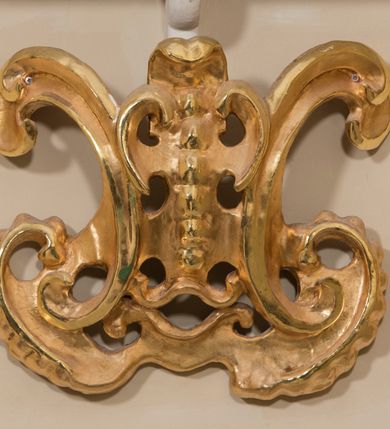 Zdjęcie nr 27: Ołtarz architektoniczny, dwukondygnacyjny, trójosiowy, ze zwieńczeniem. Ołtarz murowany, prostopadłościenny z marmurowym antepedium. Tabernakulum w formie prostopadłościennej, metalowej szafki ujętej parą ażurowych spływów wolutowych w formie stylizowanych wici akantowych. Drzwiczki, w kształcie zbliżonym do kwadratu, zdobione motywem krzyża i banderoli z napisem „IHS” ujętych kłosami zboża i kiściami winnej latorośli. Tron wystawienia w formie baldachimu wspartego na 4 kolumienkach. Krawędź zwieńczenia ujęta jest ornamentyką roślinną, w motywem kartusza z krzyżem po środku. Oś środkowa retabulum osadzona na wysokim, zdwojonym cokole o zryzalitowanych bokach. Pierwszą kondygnację ujmują dwie pary kolumn o kanelowanych trzonach i korynckich kapitelach, z czego wewnętrzne wysunięte względem lica nastawy, wspierających wyłamujące się ponad nimi belkowanie, w partii architrawu przybierające kształt  półkolistego łuku nadwieszonego; całość wieńczy forma trójkątnego przyczółka. Druga kondygnacja ujęta parą osadzonych na cokołach kolumn o trzonach zdobionych wicią winnej latorośli, wspierających delikatnie wyłamujące się ponad nimi belkowanie przerwane w partii fryzu u gzymsu. Zwieńczenie w formie trójkątnego, przerwanego przyczółka. W strefie zryzalitowanych po bokach cokołów osi bocznych para półkoliście zamkniętych bramek. Krawędzie zewnętrzne kondygnacji osi bocznych ujęte pojedynczymi kolumnami dźwigającymi wyłamujące się ponad nimi belkowanie wieńczące, będące przedłużeniem belkowania osi środkowej.  Pola cokołu retabulum wypełnione motywami ornamentyki roślinnej, w partii fryzu motywy małżowinowo-chrząstkowe. Druga kondygnacja osi środkowej ujęta parą ażurowych, małżowinowo-chrząstkowych uszaków, szczyt zwieńczenia w formie promienistej glorii z owalnym medalionem ujętym wieńcem obłoków, z monogramem imienia Jezus. Pola osi bocznych w dolnej partii zdobione motywami małżowinowo-chrząstkowego kartusza, w górnej owocowo-kwiatowymi festonami. Skrajne pola cokołu retabulum wypełnia para wizerunków – św. Pawła po prawej stronie i św. Piotra po lewej. Pole pierwszej kondygnacji osi środkowej ma formę płytkiej wnęki w kształcie stojącego prostokąta zamkniętego półkolistym łukiem nadwieszonym, ujętej bogato rzeźbioną ramą z motywem ornamentu małżowinowo-chrząstkowego, w środku obraz Matki Boskiej z Dzieciątkiem. Pole drugiej kondygnacji wypełnia obraz w kształcie leżącego prostokąta, ujęty szeroką ramą z uszakami w narożach, zdobioną ornamentem małżowinowo-chrząstkowym. Po bokach para półkoliście zamkniętych niszy z motywem konchy, wypełnionych parą figur – po prawej stronie św. Dominika, po lewej św. Antoni (?). Pola osi bocznych artykułuje para zamkniętych półkoliście niszy z motywami konchy, z parą rzeźb – św. Stanisława po prawej stronie i św. Wojciecha po lewej.  W szczycie osi bocznych pośrodku para rzeźb flankujących zwieńczenie ołtarza – po prawej stronie św. Wacława, po lewej św. Kazimierza, na końcach para figur aniołów. Struktura polichromowana w odcieniach koloru kremowego i beżowego, detal architektoniczny i ornamentyka złocone i srebrzone.