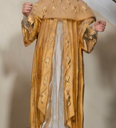 Zdjęcie nr 19: Ołtarz architektoniczny, dwukondygnacyjny, trójosiowy, ze zwieńczeniem. Ołtarz murowany, prostopadłościenny z marmurowym antepedium. Tabernakulum w formie prostopadłościennej, metalowej szafki ujętej parą ażurowych spływów wolutowych w formie stylizowanych wici akantowych. Drzwiczki, w kształcie zbliżonym do kwadratu, zdobione motywem krzyża i banderoli z napisem „IHS” ujętych kłosami zboża i kiściami winnej latorośli. Tron wystawienia w formie baldachimu wspartego na 4 kolumienkach. Krawędź zwieńczenia ujęta jest ornamentyką roślinną, w motywem kartusza z krzyżem po środku. Oś środkowa retabulum osadzona na wysokim, zdwojonym cokole o zryzalitowanych bokach. Pierwszą kondygnację ujmują dwie pary kolumn o kanelowanych trzonach i korynckich kapitelach, z czego wewnętrzne wysunięte względem lica nastawy, wspierających wyłamujące się ponad nimi belkowanie, w partii architrawu przybierające kształt  półkolistego łuku nadwieszonego; całość wieńczy forma trójkątnego przyczółka. Druga kondygnacja ujęta parą osadzonych na cokołach kolumn o trzonach zdobionych wicią winnej latorośli, wspierających delikatnie wyłamujące się ponad nimi belkowanie przerwane w partii fryzu u gzymsu. Zwieńczenie w formie trójkątnego, przerwanego przyczółka. W strefie zryzalitowanych po bokach cokołów osi bocznych para półkoliście zamkniętych bramek. Krawędzie zewnętrzne kondygnacji osi bocznych ujęte pojedynczymi kolumnami dźwigającymi wyłamujące się ponad nimi belkowanie wieńczące, będące przedłużeniem belkowania osi środkowej.  Pola cokołu retabulum wypełnione motywami ornamentyki roślinnej, w partii fryzu motywy małżowinowo-chrząstkowe. Druga kondygnacja osi środkowej ujęta parą ażurowych, małżowinowo-chrząstkowych uszaków, szczyt zwieńczenia w formie promienistej glorii z owalnym medalionem ujętym wieńcem obłoków, z monogramem imienia Jezus. Pola osi bocznych w dolnej partii zdobione motywami małżowinowo-chrząstkowego kartusza, w górnej owocowo-kwiatowymi festonami. Skrajne pola cokołu retabulum wypełnia para wizerunków – św. Pawła po prawej stronie i św. Piotra po lewej. Pole pierwszej kondygnacji osi środkowej ma formę płytkiej wnęki w kształcie stojącego prostokąta zamkniętego półkolistym łukiem nadwieszonym, ujętej bogato rzeźbioną ramą z motywem ornamentu małżowinowo-chrząstkowego, w środku obraz Matki Boskiej z Dzieciątkiem. Pole drugiej kondygnacji wypełnia obraz w kształcie leżącego prostokąta, ujęty szeroką ramą z uszakami w narożach, zdobioną ornamentem małżowinowo-chrząstkowym. Po bokach para półkoliście zamkniętych niszy z motywem konchy, wypełnionych parą figur – po prawej stronie św. Dominika, po lewej św. Antoni (?). Pola osi bocznych artykułuje para zamkniętych półkoliście niszy z motywami konchy, z parą rzeźb – św. Stanisława po prawej stronie i św. Wojciecha po lewej.  W szczycie osi bocznych pośrodku para rzeźb flankujących zwieńczenie ołtarza – po prawej stronie św. Wacława, po lewej św. Kazimierza, na końcach para figur aniołów. Struktura polichromowana w odcieniach koloru kremowego i beżowego, detal architektoniczny i ornamentyka złocone i srebrzone.