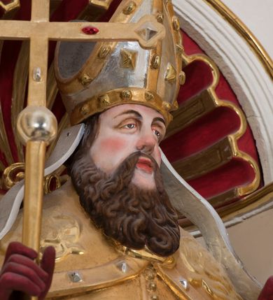 Zdjęcie nr 11: Ołtarz architektoniczny, dwukondygnacyjny, trójosiowy, ze zwieńczeniem. Ołtarz murowany, prostopadłościenny z marmurowym antepedium. Tabernakulum w formie prostopadłościennej, metalowej szafki ujętej parą ażurowych spływów wolutowych w formie stylizowanych wici akantowych. Drzwiczki, w kształcie zbliżonym do kwadratu, zdobione motywem krzyża i banderoli z napisem „IHS” ujętych kłosami zboża i kiściami winnej latorośli. Tron wystawienia w formie baldachimu wspartego na 4 kolumienkach. Krawędź zwieńczenia ujęta jest ornamentyką roślinną, w motywem kartusza z krzyżem po środku. Oś środkowa retabulum osadzona na wysokim, zdwojonym cokole o zryzalitowanych bokach. Pierwszą kondygnację ujmują dwie pary kolumn o kanelowanych trzonach i korynckich kapitelach, z czego wewnętrzne wysunięte względem lica nastawy, wspierających wyłamujące się ponad nimi belkowanie, w partii architrawu przybierające kształt  półkolistego łuku nadwieszonego; całość wieńczy forma trójkątnego przyczółka. Druga kondygnacja ujęta parą osadzonych na cokołach kolumn o trzonach zdobionych wicią winnej latorośli, wspierających delikatnie wyłamujące się ponad nimi belkowanie przerwane w partii fryzu u gzymsu. Zwieńczenie w formie trójkątnego, przerwanego przyczółka. W strefie zryzalitowanych po bokach cokołów osi bocznych para półkoliście zamkniętych bramek. Krawędzie zewnętrzne kondygnacji osi bocznych ujęte pojedynczymi kolumnami dźwigającymi wyłamujące się ponad nimi belkowanie wieńczące, będące przedłużeniem belkowania osi środkowej.  Pola cokołu retabulum wypełnione motywami ornamentyki roślinnej, w partii fryzu motywy małżowinowo-chrząstkowe. Druga kondygnacja osi środkowej ujęta parą ażurowych, małżowinowo-chrząstkowych uszaków, szczyt zwieńczenia w formie promienistej glorii z owalnym medalionem ujętym wieńcem obłoków, z monogramem imienia Jezus. Pola osi bocznych w dolnej partii zdobione motywami małżowinowo-chrząstkowego kartusza, w górnej owocowo-kwiatowymi festonami. Skrajne pola cokołu retabulum wypełnia para wizerunków – św. Pawła po prawej stronie i św. Piotra po lewej. Pole pierwszej kondygnacji osi środkowej ma formę płytkiej wnęki w kształcie stojącego prostokąta zamkniętego półkolistym łukiem nadwieszonym, ujętej bogato rzeźbioną ramą z motywem ornamentu małżowinowo-chrząstkowego, w środku obraz Matki Boskiej z Dzieciątkiem. Pole drugiej kondygnacji wypełnia obraz w kształcie leżącego prostokąta, ujęty szeroką ramą z uszakami w narożach, zdobioną ornamentem małżowinowo-chrząstkowym. Po bokach para półkoliście zamkniętych niszy z motywem konchy, wypełnionych parą figur – po prawej stronie św. Dominika, po lewej św. Antoni (?). Pola osi bocznych artykułuje para zamkniętych półkoliście niszy z motywami konchy, z parą rzeźb – św. Stanisława po prawej stronie i św. Wojciecha po lewej.  W szczycie osi bocznych pośrodku para rzeźb flankujących zwieńczenie ołtarza – po prawej stronie św. Wacława, po lewej św. Kazimierza, na końcach para figur aniołów. Struktura polichromowana w odcieniach koloru kremowego i beżowego, detal architektoniczny i ornamentyka złocone i srebrzone.