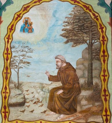 Zdjęcie nr 17: Ściany kościoła pokrywa dekoracja dywanowa, której w partiach stropu towarzyszą przedstawienia figuralne. W prezbiterium wykonano wyraźnie zaakcentowany fryz podstropowy, który od fasety oddziela profilowany i ornamentalnie malowany gzyms. Fryz na baldoniebieskim tle pokryto naprzemiennie rozmieszczonymi uskrzydlonymi główkami aniołów z niskimi wazonami z rozłożonymi trzema gałązkami kwitnących lilii. Poniżej barwnej bordiury oddzielającej fryz od pozostałych partii ścian, wykonano zgeometryzowaną dekorację utworzoną z powtarzających się wielobocznych pól, w których znalazł się stylizowany motyw tego samego kwiatu. Fasetę w prezbiterium pokryto naprzemiennie, rytmicznie rozmieszczonymi stylizowanymi kwiatami na łodydze i bez łodygi, które obwiedziono migdałowymi otokami tworzą ornamentalny pas zamknięty u góry falującą, wąską bordiurą. Dekorację bladoniebieskiego stropu prezbiterium tworzy poprowadzona przy krawędziach srebrno-niebieska arkatura. W centrum na niebieskim tle usianym złotymi gwiazdkami wyobrażono zasiadającą na obłokach Trójcę Świętą obramienioną pofalowaną, wielobarwną bordiurą otoczoną stylizowaną, srebrną wicią akantową. Dekoracyjną wić przedzielono parą uskrzydlonych główek anielskich oraz czterema stylizowanymi pąkami fantazyjnych kwiatów. Frontalnie ujęty Bóg Ojciec został wyobrażony jako siwobrody starzec o bujnych siwych włosach. W prawej ręce trzyma złote berło, lewą zaś wyciąga przed siebie. Bóg Ojciec prawą nogę opiera o niebieski glob, natomiast lewą, wyprostowaną wspiera się o obłoki. Jego twarz charakteryzuje jasna karnacja, szeroko otwarte oczy, wydatny nos i usta. Wokół głowy widać trójkąt. Obok Boga Ojca z lewej strony siedzi Chrystus, który obie nogi wspiera na globie. Zbawiciel trzymający oburącz na wysokości ramienia drewniany krzyż został przedstawiony w trzech czwartych w prawo. Jest to dojrzały mężczyzna o pociągłej twarzy okolonej brązowymi, długimi włosami spływającymi na ramiona oraz brodą. Ma jasną karnację, prosty nos i wydatne usta. Jego melancholijne spojrzenie jest skierowane w bok. Nagi tors okrywa bladoszkarłatny płaszcz odsłaniający prawą nogę. Na dłoniach i stopach widoczne są rany po gwoździach. Głowę Jezusa okala świetlisty nimb. Powyżej obu postaci unosi się gołębica Ducha Świętego w promienistym otoku. Niebieski glob na tle obłoków unoszą dwa aniołki w przepaskach. W nawie kościoła dekorację tworzą trzy różnej szerokości poziome pasy ornamentalne ułożone ponad jednolitą, szarą lamperią. Najszerszy pas pokryto na jasnym tle zgeometryzowanym ornamentem utworzonym z ciemnocynobrowych, migdałowo kształtowanych pól naśladujących wić roślinną. Powyżej rozmieszczono rytmicznie ułożone stylizowane krzyże równoramienne w fantazyjnych, wielobarwnych obramieniach. Najwyższy pas, odpowiadający fryzowi podstropowemu w prezbiterium pokryto wicią winnej latorośli z wplecionymi pękami kłosów. Tą część dekoracji zamyka profilowany gzyms ozdobiony wielobarwnym ornamentem zgeomertyzowanym. Rozpościerającą się ponad nim fasetę ozdobiono rytmicznie rozmieszczonym białym kwiatem na łodydze naśladujący w kształcie grzebień wodny. Dekorację bladoniebieskiego stropu artykułowano za pomocą srebrnej arkatury poprowadzonej przy jego krawędziach oraz ornamentalnych pasów utworzonych z motywów floralnych i geometrycznych, tworzących czworoboczną ramę dla centralnej kompozycji figuralnej. W narożach tego obramienia umieszczono medaliony ukazujące w popiersiach czterech ewangelistów malowanych na blasze miedzianej. Medaliony otaczają stylizowane gałązki dębowe z żołędziami. Każdego ewangelistę identyfikuje jego atrybut. W centrum stropu na bladozielonym tle usianym srebrnymi gwiazdkami namalowano wydłużone owalne obramienie utworzone z szerokiego wieńca różanego o bardzo drobnych kwiatach różanych i listkach. W jego centrum na tle bladoniebieskich obłoków ze złotymi gwiazdkami, bezpośrednio na deskach stropu, przedstawiono stojącą Madonnę z Dzieciątkiem, która depcze węża. Dodatkowo postać Marii zdaje się stać na rozpiętym różańcu. Maria ujęta frontalnie w kontrapoście obiema rękami podtrzymuje na prawym ramieniu Dzieciątko. Ma pociągłą twarz o jasnej karnacji, prostym nosie i wąskich ustach. Spojrzenie jej przymkniętych oczu jest skierowane w dół. Na głowie ma chustę szczelnie okrywającą jej włosy oraz złotą koronę o niskich sterczynach. Madonna ubrana jest w bladoczerwoną suknię odsłaniającą bosą stopę, którą depcze węża. Spod sukni na piersi widać białą koszulę. Na ramionach ma błękitny płaszcz podbity jasną ochrą, spięty na piersi podłużną, złotą klamrą. Trzymane przez nią Dzieciątko ma rozłożone ręce z uniesionymi dłońmi. Jego głowa ujęta jest w trzech czwartych w prawo. Otaczają ją jasno brązowe, krótkie włosy. Mały Jezus ubrany jest w jasną tunikę odsłaniającą jego bose stopy. Wokół Matki Boskiej rozmieszczono owalne medaliony z blachy miedzianej malowane w piętnaście tajemnic Różańca świętego. Ich narracja rozpoczyna się nad głową Madonny. Każda ze scen oparta jest o kilkuosobową kompozycję. Idąc w lewo namalowano: Zwiastowanie Marii, Nawiedzenie św. Elżbiety, Boże Narodzenie, Ofiarowanie w świątyni, Znalezienie w świątyni, Modlitwa w Ogrójcu, Biczowanie, Cierniem ukoronowanie, Niesienie krzyża, Ukrzyżowanie, Zmartwychwstanie, Wniebowstąpienie, Zesłanie Ducha Świętego, Wniebowzięcie Marii, Ukoronowanie Marii w niebie. Pomiędzy medalionami namalowano białą i czerwoną różę. Jasny parapet chóru muzycznego udekorowano naprzemiennie rozmieszczonymi rytmicznie stylizowanymi łodygami zakończonymi białymi pąkami i krzyżami równoramiennymi wpisanymi w koło. W aneksie południowym namalowano na ścianie kazanie św. Franciszka z Asyżu do ptaków. Kompozycja uzyskała kształt wydłużonego, stojącego prostokąta zamkniętego półkoliście i obwiedzionego falującą bordiurą z motywem łączących się krzyżyków. W jej centrum wyobrażono siedzącego na skalnym podłożu św. Franciszka ujętego w trzech czwartych w lewo. Święty prawą rękę unosi w geście mowy lewą zaś swobodnie trzyma na kolanach. Jego widoczną z profilu twarz o jasnej karnacji i prostym nosie okala siwiejąca broda i włosy z wyciętą tonsurą. Ubrany jest w brązowy habit przewiązany sznurem. Przed Franciszkiem przedstawiono stadko słuchających świetego ptaków. W prawym rogu kompozycji namalowano drewniane taczki. Z tyłu za świętym na tle skał rośnie drzewo. Inne drzewo wyobrażono z lewej strony, nieco z tyłu, na tle nieba pokrytego baldoniebieskimi obłokami. U góry z lewej strony na tle obłoków widać niewielką postać Madonny z Dzieciątkiem w typie Matki Boskiej Częstochowskiej.      