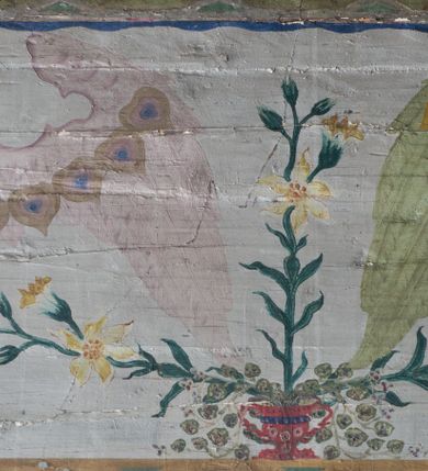 Zdjęcie nr 14: Ściany kościoła pokrywa dekoracja dywanowa, której w partiach stropu towarzyszą przedstawienia figuralne. W prezbiterium wykonano wyraźnie zaakcentowany fryz podstropowy, który od fasety oddziela profilowany i ornamentalnie malowany gzyms. Fryz na baldoniebieskim tle pokryto naprzemiennie rozmieszczonymi uskrzydlonymi główkami aniołów z niskimi wazonami z rozłożonymi trzema gałązkami kwitnących lilii. Poniżej barwnej bordiury oddzielającej fryz od pozostałych partii ścian, wykonano zgeometryzowaną dekorację utworzoną z powtarzających się wielobocznych pól, w których znalazł się stylizowany motyw tego samego kwiatu. Fasetę w prezbiterium pokryto naprzemiennie, rytmicznie rozmieszczonymi stylizowanymi kwiatami na łodydze i bez łodygi, które obwiedziono migdałowymi otokami tworzą ornamentalny pas zamknięty u góry falującą, wąską bordiurą. Dekorację bladoniebieskiego stropu prezbiterium tworzy poprowadzona przy krawędziach srebrno-niebieska arkatura. W centrum na niebieskim tle usianym złotymi gwiazdkami wyobrażono zasiadającą na obłokach Trójcę Świętą obramienioną pofalowaną, wielobarwną bordiurą otoczoną stylizowaną, srebrną wicią akantową. Dekoracyjną wić przedzielono parą uskrzydlonych główek anielskich oraz czterema stylizowanymi pąkami fantazyjnych kwiatów. Frontalnie ujęty Bóg Ojciec został wyobrażony jako siwobrody starzec o bujnych siwych włosach. W prawej ręce trzyma złote berło, lewą zaś wyciąga przed siebie. Bóg Ojciec prawą nogę opiera o niebieski glob, natomiast lewą, wyprostowaną wspiera się o obłoki. Jego twarz charakteryzuje jasna karnacja, szeroko otwarte oczy, wydatny nos i usta. Wokół głowy widać trójkąt. Obok Boga Ojca z lewej strony siedzi Chrystus, który obie nogi wspiera na globie. Zbawiciel trzymający oburącz na wysokości ramienia drewniany krzyż został przedstawiony w trzech czwartych w prawo. Jest to dojrzały mężczyzna o pociągłej twarzy okolonej brązowymi, długimi włosami spływającymi na ramiona oraz brodą. Ma jasną karnację, prosty nos i wydatne usta. Jego melancholijne spojrzenie jest skierowane w bok. Nagi tors okrywa bladoszkarłatny płaszcz odsłaniający prawą nogę. Na dłoniach i stopach widoczne są rany po gwoździach. Głowę Jezusa okala świetlisty nimb. Powyżej obu postaci unosi się gołębica Ducha Świętego w promienistym otoku. Niebieski glob na tle obłoków unoszą dwa aniołki w przepaskach. W nawie kościoła dekorację tworzą trzy różnej szerokości poziome pasy ornamentalne ułożone ponad jednolitą, szarą lamperią. Najszerszy pas pokryto na jasnym tle zgeometryzowanym ornamentem utworzonym z ciemnocynobrowych, migdałowo kształtowanych pól naśladujących wić roślinną. Powyżej rozmieszczono rytmicznie ułożone stylizowane krzyże równoramienne w fantazyjnych, wielobarwnych obramieniach. Najwyższy pas, odpowiadający fryzowi podstropowemu w prezbiterium pokryto wicią winnej latorośli z wplecionymi pękami kłosów. Tą część dekoracji zamyka profilowany gzyms ozdobiony wielobarwnym ornamentem zgeomertyzowanym. Rozpościerającą się ponad nim fasetę ozdobiono rytmicznie rozmieszczonym białym kwiatem na łodydze naśladujący w kształcie grzebień wodny. Dekorację bladoniebieskiego stropu artykułowano za pomocą srebrnej arkatury poprowadzonej przy jego krawędziach oraz ornamentalnych pasów utworzonych z motywów floralnych i geometrycznych, tworzących czworoboczną ramę dla centralnej kompozycji figuralnej. W narożach tego obramienia umieszczono medaliony ukazujące w popiersiach czterech ewangelistów malowanych na blasze miedzianej. Medaliony otaczają stylizowane gałązki dębowe z żołędziami. Każdego ewangelistę identyfikuje jego atrybut. W centrum stropu na bladozielonym tle usianym srebrnymi gwiazdkami namalowano wydłużone owalne obramienie utworzone z szerokiego wieńca różanego o bardzo drobnych kwiatach różanych i listkach. W jego centrum na tle bladoniebieskich obłoków ze złotymi gwiazdkami, bezpośrednio na deskach stropu, przedstawiono stojącą Madonnę z Dzieciątkiem, która depcze węża. Dodatkowo postać Marii zdaje się stać na rozpiętym różańcu. Maria ujęta frontalnie w kontrapoście obiema rękami podtrzymuje na prawym ramieniu Dzieciątko. Ma pociągłą twarz o jasnej karnacji, prostym nosie i wąskich ustach. Spojrzenie jej przymkniętych oczu jest skierowane w dół. Na głowie ma chustę szczelnie okrywającą jej włosy oraz złotą koronę o niskich sterczynach. Madonna ubrana jest w bladoczerwoną suknię odsłaniającą bosą stopę, którą depcze węża. Spod sukni na piersi widać białą koszulę. Na ramionach ma błękitny płaszcz podbity jasną ochrą, spięty na piersi podłużną, złotą klamrą. Trzymane przez nią Dzieciątko ma rozłożone ręce z uniesionymi dłońmi. Jego głowa ujęta jest w trzech czwartych w prawo. Otaczają ją jasno brązowe, krótkie włosy. Mały Jezus ubrany jest w jasną tunikę odsłaniającą jego bose stopy. Wokół Matki Boskiej rozmieszczono owalne medaliony z blachy miedzianej malowane w piętnaście tajemnic Różańca świętego. Ich narracja rozpoczyna się nad głową Madonny. Każda ze scen oparta jest o kilkuosobową kompozycję. Idąc w lewo namalowano: Zwiastowanie Marii, Nawiedzenie św. Elżbiety, Boże Narodzenie, Ofiarowanie w świątyni, Znalezienie w świątyni, Modlitwa w Ogrójcu, Biczowanie, Cierniem ukoronowanie, Niesienie krzyża, Ukrzyżowanie, Zmartwychwstanie, Wniebowstąpienie, Zesłanie Ducha Świętego, Wniebowzięcie Marii, Ukoronowanie Marii w niebie. Pomiędzy medalionami namalowano białą i czerwoną różę. Jasny parapet chóru muzycznego udekorowano naprzemiennie rozmieszczonymi rytmicznie stylizowanymi łodygami zakończonymi białymi pąkami i krzyżami równoramiennymi wpisanymi w koło. W aneksie południowym namalowano na ścianie kazanie św. Franciszka z Asyżu do ptaków. Kompozycja uzyskała kształt wydłużonego, stojącego prostokąta zamkniętego półkoliście i obwiedzionego falującą bordiurą z motywem łączących się krzyżyków. W jej centrum wyobrażono siedzącego na skalnym podłożu św. Franciszka ujętego w trzech czwartych w lewo. Święty prawą rękę unosi w geście mowy lewą zaś swobodnie trzyma na kolanach. Jego widoczną z profilu twarz o jasnej karnacji i prostym nosie okala siwiejąca broda i włosy z wyciętą tonsurą. Ubrany jest w brązowy habit przewiązany sznurem. Przed Franciszkiem przedstawiono stadko słuchających świetego ptaków. W prawym rogu kompozycji namalowano drewniane taczki. Z tyłu za świętym na tle skał rośnie drzewo. Inne drzewo wyobrażono z lewej strony, nieco z tyłu, na tle nieba pokrytego baldoniebieskimi obłokami. U góry z lewej strony na tle obłoków widać niewielką postać Madonny z Dzieciątkiem w typie Matki Boskiej Częstochowskiej.      