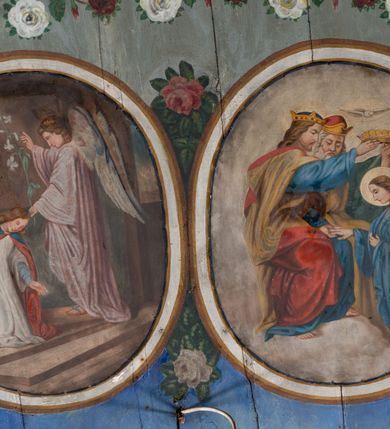 Zdjęcie nr 23: Ściany kościoła pokrywa dekoracja dywanowa, której w partiach stropu towarzyszą przedstawienia figuralne. W prezbiterium wykonano wyraźnie zaakcentowany fryz podstropowy, który od fasety oddziela profilowany i ornamentalnie malowany gzyms. Fryz na baldoniebieskim tle pokryto naprzemiennie rozmieszczonymi uskrzydlonymi główkami aniołów z niskimi wazonami z rozłożonymi trzema gałązkami kwitnących lilii. Poniżej barwnej bordiury oddzielającej fryz od pozostałych partii ścian, wykonano zgeometryzowaną dekorację utworzoną z powtarzających się wielobocznych pól, w których znalazł się stylizowany motyw tego samego kwiatu. Fasetę w prezbiterium pokryto naprzemiennie, rytmicznie rozmieszczonymi stylizowanymi kwiatami na łodydze i bez łodygi, które obwiedziono migdałowymi otokami tworzą ornamentalny pas zamknięty u góry falującą, wąską bordiurą. Dekorację bladoniebieskiego stropu prezbiterium tworzy poprowadzona przy krawędziach srebrno-niebieska arkatura. W centrum na niebieskim tle usianym złotymi gwiazdkami wyobrażono zasiadającą na obłokach Trójcę Świętą obramienioną pofalowaną, wielobarwną bordiurą otoczoną stylizowaną, srebrną wicią akantową. Dekoracyjną wić przedzielono parą uskrzydlonych główek anielskich oraz czterema stylizowanymi pąkami fantazyjnych kwiatów. Frontalnie ujęty Bóg Ojciec został wyobrażony jako siwobrody starzec o bujnych siwych włosach. W prawej ręce trzyma złote berło, lewą zaś wyciąga przed siebie. Bóg Ojciec prawą nogę opiera o niebieski glob, natomiast lewą, wyprostowaną wspiera się o obłoki. Jego twarz charakteryzuje jasna karnacja, szeroko otwarte oczy, wydatny nos i usta. Wokół głowy widać trójkąt. Obok Boga Ojca z lewej strony siedzi Chrystus, który obie nogi wspiera na globie. Zbawiciel trzymający oburącz na wysokości ramienia drewniany krzyż został przedstawiony w trzech czwartych w prawo. Jest to dojrzały mężczyzna o pociągłej twarzy okolonej brązowymi, długimi włosami spływającymi na ramiona oraz brodą. Ma jasną karnację, prosty nos i wydatne usta. Jego melancholijne spojrzenie jest skierowane w bok. Nagi tors okrywa bladoszkarłatny płaszcz odsłaniający prawą nogę. Na dłoniach i stopach widoczne są rany po gwoździach. Głowę Jezusa okala świetlisty nimb. Powyżej obu postaci unosi się gołębica Ducha Świętego w promienistym otoku. Niebieski glob na tle obłoków unoszą dwa aniołki w przepaskach. W nawie kościoła dekorację tworzą trzy różnej szerokości poziome pasy ornamentalne ułożone ponad jednolitą, szarą lamperią. Najszerszy pas pokryto na jasnym tle zgeometryzowanym ornamentem utworzonym z ciemnocynobrowych, migdałowo kształtowanych pól naśladujących wić roślinną. Powyżej rozmieszczono rytmicznie ułożone stylizowane krzyże równoramienne w fantazyjnych, wielobarwnych obramieniach. Najwyższy pas, odpowiadający fryzowi podstropowemu w prezbiterium pokryto wicią winnej latorośli z wplecionymi pękami kłosów. Tą część dekoracji zamyka profilowany gzyms ozdobiony wielobarwnym ornamentem zgeomertyzowanym. Rozpościerającą się ponad nim fasetę ozdobiono rytmicznie rozmieszczonym białym kwiatem na łodydze naśladujący w kształcie grzebień wodny. Dekorację bladoniebieskiego stropu artykułowano za pomocą srebrnej arkatury poprowadzonej przy jego krawędziach oraz ornamentalnych pasów utworzonych z motywów floralnych i geometrycznych, tworzących czworoboczną ramę dla centralnej kompozycji figuralnej. W narożach tego obramienia umieszczono medaliony ukazujące w popiersiach czterech ewangelistów malowanych na blasze miedzianej. Medaliony otaczają stylizowane gałązki dębowe z żołędziami. Każdego ewangelistę identyfikuje jego atrybut. W centrum stropu na bladozielonym tle usianym srebrnymi gwiazdkami namalowano wydłużone owalne obramienie utworzone z szerokiego wieńca różanego o bardzo drobnych kwiatach różanych i listkach. W jego centrum na tle bladoniebieskich obłoków ze złotymi gwiazdkami, bezpośrednio na deskach stropu, przedstawiono stojącą Madonnę z Dzieciątkiem, która depcze węża. Dodatkowo postać Marii zdaje się stać na rozpiętym różańcu. Maria ujęta frontalnie w kontrapoście obiema rękami podtrzymuje na prawym ramieniu Dzieciątko. Ma pociągłą twarz o jasnej karnacji, prostym nosie i wąskich ustach. Spojrzenie jej przymkniętych oczu jest skierowane w dół. Na głowie ma chustę szczelnie okrywającą jej włosy oraz złotą koronę o niskich sterczynach. Madonna ubrana jest w bladoczerwoną suknię odsłaniającą bosą stopę, którą depcze węża. Spod sukni na piersi widać białą koszulę. Na ramionach ma błękitny płaszcz podbity jasną ochrą, spięty na piersi podłużną, złotą klamrą. Trzymane przez nią Dzieciątko ma rozłożone ręce z uniesionymi dłońmi. Jego głowa ujęta jest w trzech czwartych w prawo. Otaczają ją jasno brązowe, krótkie włosy. Mały Jezus ubrany jest w jasną tunikę odsłaniającą jego bose stopy. Wokół Matki Boskiej rozmieszczono owalne medaliony z blachy miedzianej malowane w piętnaście tajemnic Różańca świętego. Ich narracja rozpoczyna się nad głową Madonny. Każda ze scen oparta jest o kilkuosobową kompozycję. Idąc w lewo namalowano: Zwiastowanie Marii, Nawiedzenie św. Elżbiety, Boże Narodzenie, Ofiarowanie w świątyni, Znalezienie w świątyni, Modlitwa w Ogrójcu, Biczowanie, Cierniem ukoronowanie, Niesienie krzyża, Ukrzyżowanie, Zmartwychwstanie, Wniebowstąpienie, Zesłanie Ducha Świętego, Wniebowzięcie Marii, Ukoronowanie Marii w niebie. Pomiędzy medalionami namalowano białą i czerwoną różę. Jasny parapet chóru muzycznego udekorowano naprzemiennie rozmieszczonymi rytmicznie stylizowanymi łodygami zakończonymi białymi pąkami i krzyżami równoramiennymi wpisanymi w koło. W aneksie południowym namalowano na ścianie kazanie św. Franciszka z Asyżu do ptaków. Kompozycja uzyskała kształt wydłużonego, stojącego prostokąta zamkniętego półkoliście i obwiedzionego falującą bordiurą z motywem łączących się krzyżyków. W jej centrum wyobrażono siedzącego na skalnym podłożu św. Franciszka ujętego w trzech czwartych w lewo. Święty prawą rękę unosi w geście mowy lewą zaś swobodnie trzyma na kolanach. Jego widoczną z profilu twarz o jasnej karnacji i prostym nosie okala siwiejąca broda i włosy z wyciętą tonsurą. Ubrany jest w brązowy habit przewiązany sznurem. Przed Franciszkiem przedstawiono stadko słuchających świetego ptaków. W prawym rogu kompozycji namalowano drewniane taczki. Z tyłu za świętym na tle skał rośnie drzewo. Inne drzewo wyobrażono z lewej strony, nieco z tyłu, na tle nieba pokrytego baldoniebieskimi obłokami. U góry z lewej strony na tle obłoków widać niewielką postać Madonny z Dzieciątkiem w typie Matki Boskiej Częstochowskiej.      