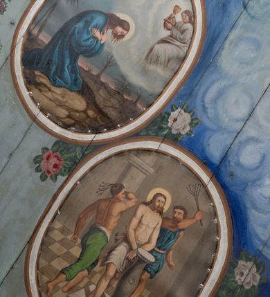 Zdjęcie nr 27: Ściany kościoła pokrywa dekoracja dywanowa, której w partiach stropu towarzyszą przedstawienia figuralne. W prezbiterium wykonano wyraźnie zaakcentowany fryz podstropowy, który od fasety oddziela profilowany i ornamentalnie malowany gzyms. Fryz na baldoniebieskim tle pokryto naprzemiennie rozmieszczonymi uskrzydlonymi główkami aniołów z niskimi wazonami z rozłożonymi trzema gałązkami kwitnących lilii. Poniżej barwnej bordiury oddzielającej fryz od pozostałych partii ścian, wykonano zgeometryzowaną dekorację utworzoną z powtarzających się wielobocznych pól, w których znalazł się stylizowany motyw tego samego kwiatu. Fasetę w prezbiterium pokryto naprzemiennie, rytmicznie rozmieszczonymi stylizowanymi kwiatami na łodydze i bez łodygi, które obwiedziono migdałowymi otokami tworzą ornamentalny pas zamknięty u góry falującą, wąską bordiurą. Dekorację bladoniebieskiego stropu prezbiterium tworzy poprowadzona przy krawędziach srebrno-niebieska arkatura. W centrum na niebieskim tle usianym złotymi gwiazdkami wyobrażono zasiadającą na obłokach Trójcę Świętą obramienioną pofalowaną, wielobarwną bordiurą otoczoną stylizowaną, srebrną wicią akantową. Dekoracyjną wić przedzielono parą uskrzydlonych główek anielskich oraz czterema stylizowanymi pąkami fantazyjnych kwiatów. Frontalnie ujęty Bóg Ojciec został wyobrażony jako siwobrody starzec o bujnych siwych włosach. W prawej ręce trzyma złote berło, lewą zaś wyciąga przed siebie. Bóg Ojciec prawą nogę opiera o niebieski glob, natomiast lewą, wyprostowaną wspiera się o obłoki. Jego twarz charakteryzuje jasna karnacja, szeroko otwarte oczy, wydatny nos i usta. Wokół głowy widać trójkąt. Obok Boga Ojca z lewej strony siedzi Chrystus, który obie nogi wspiera na globie. Zbawiciel trzymający oburącz na wysokości ramienia drewniany krzyż został przedstawiony w trzech czwartych w prawo. Jest to dojrzały mężczyzna o pociągłej twarzy okolonej brązowymi, długimi włosami spływającymi na ramiona oraz brodą. Ma jasną karnację, prosty nos i wydatne usta. Jego melancholijne spojrzenie jest skierowane w bok. Nagi tors okrywa bladoszkarłatny płaszcz odsłaniający prawą nogę. Na dłoniach i stopach widoczne są rany po gwoździach. Głowę Jezusa okala świetlisty nimb. Powyżej obu postaci unosi się gołębica Ducha Świętego w promienistym otoku. Niebieski glob na tle obłoków unoszą dwa aniołki w przepaskach. W nawie kościoła dekorację tworzą trzy różnej szerokości poziome pasy ornamentalne ułożone ponad jednolitą, szarą lamperią. Najszerszy pas pokryto na jasnym tle zgeometryzowanym ornamentem utworzonym z ciemnocynobrowych, migdałowo kształtowanych pól naśladujących wić roślinną. Powyżej rozmieszczono rytmicznie ułożone stylizowane krzyże równoramienne w fantazyjnych, wielobarwnych obramieniach. Najwyższy pas, odpowiadający fryzowi podstropowemu w prezbiterium pokryto wicią winnej latorośli z wplecionymi pękami kłosów. Tą część dekoracji zamyka profilowany gzyms ozdobiony wielobarwnym ornamentem zgeomertyzowanym. Rozpościerającą się ponad nim fasetę ozdobiono rytmicznie rozmieszczonym białym kwiatem na łodydze naśladujący w kształcie grzebień wodny. Dekorację bladoniebieskiego stropu artykułowano za pomocą srebrnej arkatury poprowadzonej przy jego krawędziach oraz ornamentalnych pasów utworzonych z motywów floralnych i geometrycznych, tworzących czworoboczną ramę dla centralnej kompozycji figuralnej. W narożach tego obramienia umieszczono medaliony ukazujące w popiersiach czterech ewangelistów malowanych na blasze miedzianej. Medaliony otaczają stylizowane gałązki dębowe z żołędziami. Każdego ewangelistę identyfikuje jego atrybut. W centrum stropu na bladozielonym tle usianym srebrnymi gwiazdkami namalowano wydłużone owalne obramienie utworzone z szerokiego wieńca różanego o bardzo drobnych kwiatach różanych i listkach. W jego centrum na tle bladoniebieskich obłoków ze złotymi gwiazdkami, bezpośrednio na deskach stropu, przedstawiono stojącą Madonnę z Dzieciątkiem, która depcze węża. Dodatkowo postać Marii zdaje się stać na rozpiętym różańcu. Maria ujęta frontalnie w kontrapoście obiema rękami podtrzymuje na prawym ramieniu Dzieciątko. Ma pociągłą twarz o jasnej karnacji, prostym nosie i wąskich ustach. Spojrzenie jej przymkniętych oczu jest skierowane w dół. Na głowie ma chustę szczelnie okrywającą jej włosy oraz złotą koronę o niskich sterczynach. Madonna ubrana jest w bladoczerwoną suknię odsłaniającą bosą stopę, którą depcze węża. Spod sukni na piersi widać białą koszulę. Na ramionach ma błękitny płaszcz podbity jasną ochrą, spięty na piersi podłużną, złotą klamrą. Trzymane przez nią Dzieciątko ma rozłożone ręce z uniesionymi dłońmi. Jego głowa ujęta jest w trzech czwartych w prawo. Otaczają ją jasno brązowe, krótkie włosy. Mały Jezus ubrany jest w jasną tunikę odsłaniającą jego bose stopy. Wokół Matki Boskiej rozmieszczono owalne medaliony z blachy miedzianej malowane w piętnaście tajemnic Różańca świętego. Ich narracja rozpoczyna się nad głową Madonny. Każda ze scen oparta jest o kilkuosobową kompozycję. Idąc w lewo namalowano: Zwiastowanie Marii, Nawiedzenie św. Elżbiety, Boże Narodzenie, Ofiarowanie w świątyni, Znalezienie w świątyni, Modlitwa w Ogrójcu, Biczowanie, Cierniem ukoronowanie, Niesienie krzyża, Ukrzyżowanie, Zmartwychwstanie, Wniebowstąpienie, Zesłanie Ducha Świętego, Wniebowzięcie Marii, Ukoronowanie Marii w niebie. Pomiędzy medalionami namalowano białą i czerwoną różę. Jasny parapet chóru muzycznego udekorowano naprzemiennie rozmieszczonymi rytmicznie stylizowanymi łodygami zakończonymi białymi pąkami i krzyżami równoramiennymi wpisanymi w koło. W aneksie południowym namalowano na ścianie kazanie św. Franciszka z Asyżu do ptaków. Kompozycja uzyskała kształt wydłużonego, stojącego prostokąta zamkniętego półkoliście i obwiedzionego falującą bordiurą z motywem łączących się krzyżyków. W jej centrum wyobrażono siedzącego na skalnym podłożu św. Franciszka ujętego w trzech czwartych w lewo. Święty prawą rękę unosi w geście mowy lewą zaś swobodnie trzyma na kolanach. Jego widoczną z profilu twarz o jasnej karnacji i prostym nosie okala siwiejąca broda i włosy z wyciętą tonsurą. Ubrany jest w brązowy habit przewiązany sznurem. Przed Franciszkiem przedstawiono stadko słuchających świetego ptaków. W prawym rogu kompozycji namalowano drewniane taczki. Z tyłu za świętym na tle skał rośnie drzewo. Inne drzewo wyobrażono z lewej strony, nieco z tyłu, na tle nieba pokrytego baldoniebieskimi obłokami. U góry z lewej strony na tle obłoków widać niewielką postać Madonny z Dzieciątkiem w typie Matki Boskiej Częstochowskiej.      