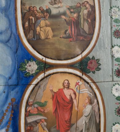 Zdjęcie nr 6: Ściany kościoła pokrywa dekoracja dywanowa, której w partiach stropu towarzyszą przedstawienia figuralne. W prezbiterium wykonano wyraźnie zaakcentowany fryz podstropowy, który od fasety oddziela profilowany i ornamentalnie malowany gzyms. Fryz na baldoniebieskim tle pokryto naprzemiennie rozmieszczonymi uskrzydlonymi główkami aniołów z niskimi wazonami z rozłożonymi trzema gałązkami kwitnących lilii. Poniżej barwnej bordiury oddzielającej fryz od pozostałych partii ścian, wykonano zgeometryzowaną dekorację utworzoną z powtarzających się wielobocznych pól, w których znalazł się stylizowany motyw tego samego kwiatu. Fasetę w prezbiterium pokryto naprzemiennie, rytmicznie rozmieszczonymi stylizowanymi kwiatami na łodydze i bez łodygi, które obwiedziono migdałowymi otokami tworzą ornamentalny pas zamknięty u góry falującą, wąską bordiurą. Dekorację bladoniebieskiego stropu prezbiterium tworzy poprowadzona przy krawędziach srebrno-niebieska arkatura. W centrum na niebieskim tle usianym złotymi gwiazdkami wyobrażono zasiadającą na obłokach Trójcę Świętą obramienioną pofalowaną, wielobarwną bordiurą otoczoną stylizowaną, srebrną wicią akantową. Dekoracyjną wić przedzielono parą uskrzydlonych główek anielskich oraz czterema stylizowanymi pąkami fantazyjnych kwiatów. Frontalnie ujęty Bóg Ojciec został wyobrażony jako siwobrody starzec o bujnych siwych włosach. W prawej ręce trzyma złote berło, lewą zaś wyciąga przed siebie. Bóg Ojciec prawą nogę opiera o niebieski glob, natomiast lewą, wyprostowaną wspiera się o obłoki. Jego twarz charakteryzuje jasna karnacja, szeroko otwarte oczy, wydatny nos i usta. Wokół głowy widać trójkąt. Obok Boga Ojca z lewej strony siedzi Chrystus, który obie nogi wspiera na globie. Zbawiciel trzymający oburącz na wysokości ramienia drewniany krzyż został przedstawiony w trzech czwartych w prawo. Jest to dojrzały mężczyzna o pociągłej twarzy okolonej brązowymi, długimi włosami spływającymi na ramiona oraz brodą. Ma jasną karnację, prosty nos i wydatne usta. Jego melancholijne spojrzenie jest skierowane w bok. Nagi tors okrywa bladoszkarłatny płaszcz odsłaniający prawą nogę. Na dłoniach i stopach widoczne są rany po gwoździach. Głowę Jezusa okala świetlisty nimb. Powyżej obu postaci unosi się gołębica Ducha Świętego w promienistym otoku. Niebieski glob na tle obłoków unoszą dwa aniołki w przepaskach. W nawie kościoła dekorację tworzą trzy różnej szerokości poziome pasy ornamentalne ułożone ponad jednolitą, szarą lamperią. Najszerszy pas pokryto na jasnym tle zgeometryzowanym ornamentem utworzonym z ciemnocynobrowych, migdałowo kształtowanych pól naśladujących wić roślinną. Powyżej rozmieszczono rytmicznie ułożone stylizowane krzyże równoramienne w fantazyjnych, wielobarwnych obramieniach. Najwyższy pas, odpowiadający fryzowi podstropowemu w prezbiterium pokryto wicią winnej latorośli z wplecionymi pękami kłosów. Tą część dekoracji zamyka profilowany gzyms ozdobiony wielobarwnym ornamentem zgeomertyzowanym. Rozpościerającą się ponad nim fasetę ozdobiono rytmicznie rozmieszczonym białym kwiatem na łodydze naśladujący w kształcie grzebień wodny. Dekorację bladoniebieskiego stropu artykułowano za pomocą srebrnej arkatury poprowadzonej przy jego krawędziach oraz ornamentalnych pasów utworzonych z motywów floralnych i geometrycznych, tworzących czworoboczną ramę dla centralnej kompozycji figuralnej. W narożach tego obramienia umieszczono medaliony ukazujące w popiersiach czterech ewangelistów malowanych na blasze miedzianej. Medaliony otaczają stylizowane gałązki dębowe z żołędziami. Każdego ewangelistę identyfikuje jego atrybut. W centrum stropu na bladozielonym tle usianym srebrnymi gwiazdkami namalowano wydłużone owalne obramienie utworzone z szerokiego wieńca różanego o bardzo drobnych kwiatach różanych i listkach. W jego centrum na tle bladoniebieskich obłoków ze złotymi gwiazdkami, bezpośrednio na deskach stropu, przedstawiono stojącą Madonnę z Dzieciątkiem, która depcze węża. Dodatkowo postać Marii zdaje się stać na rozpiętym różańcu. Maria ujęta frontalnie w kontrapoście obiema rękami podtrzymuje na prawym ramieniu Dzieciątko. Ma pociągłą twarz o jasnej karnacji, prostym nosie i wąskich ustach. Spojrzenie jej przymkniętych oczu jest skierowane w dół. Na głowie ma chustę szczelnie okrywającą jej włosy oraz złotą koronę o niskich sterczynach. Madonna ubrana jest w bladoczerwoną suknię odsłaniającą bosą stopę, którą depcze węża. Spod sukni na piersi widać białą koszulę. Na ramionach ma błękitny płaszcz podbity jasną ochrą, spięty na piersi podłużną, złotą klamrą. Trzymane przez nią Dzieciątko ma rozłożone ręce z uniesionymi dłońmi. Jego głowa ujęta jest w trzech czwartych w prawo. Otaczają ją jasno brązowe, krótkie włosy. Mały Jezus ubrany jest w jasną tunikę odsłaniającą jego bose stopy. Wokół Matki Boskiej rozmieszczono owalne medaliony z blachy miedzianej malowane w piętnaście tajemnic Różańca świętego. Ich narracja rozpoczyna się nad głową Madonny. Każda ze scen oparta jest o kilkuosobową kompozycję. Idąc w lewo namalowano: Zwiastowanie Marii, Nawiedzenie św. Elżbiety, Boże Narodzenie, Ofiarowanie w świątyni, Znalezienie w świątyni, Modlitwa w Ogrójcu, Biczowanie, Cierniem ukoronowanie, Niesienie krzyża, Ukrzyżowanie, Zmartwychwstanie, Wniebowstąpienie, Zesłanie Ducha Świętego, Wniebowzięcie Marii, Ukoronowanie Marii w niebie. Pomiędzy medalionami namalowano białą i czerwoną różę. Jasny parapet chóru muzycznego udekorowano naprzemiennie rozmieszczonymi rytmicznie stylizowanymi łodygami zakończonymi białymi pąkami i krzyżami równoramiennymi wpisanymi w koło. W aneksie południowym namalowano na ścianie kazanie św. Franciszka z Asyżu do ptaków. Kompozycja uzyskała kształt wydłużonego, stojącego prostokąta zamkniętego półkoliście i obwiedzionego falującą bordiurą z motywem łączących się krzyżyków. W jej centrum wyobrażono siedzącego na skalnym podłożu św. Franciszka ujętego w trzech czwartych w lewo. Święty prawą rękę unosi w geście mowy lewą zaś swobodnie trzyma na kolanach. Jego widoczną z profilu twarz o jasnej karnacji i prostym nosie okala siwiejąca broda i włosy z wyciętą tonsurą. Ubrany jest w brązowy habit przewiązany sznurem. Przed Franciszkiem przedstawiono stadko słuchających świetego ptaków. W prawym rogu kompozycji namalowano drewniane taczki. Z tyłu za świętym na tle skał rośnie drzewo. Inne drzewo wyobrażono z lewej strony, nieco z tyłu, na tle nieba pokrytego baldoniebieskimi obłokami. U góry z lewej strony na tle obłoków widać niewielką postać Madonny z Dzieciątkiem w typie Matki Boskiej Częstochowskiej.      