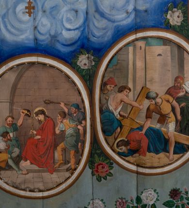 Zdjęcie nr 3: Ściany kościoła pokrywa dekoracja dywanowa, której w partiach stropu towarzyszą przedstawienia figuralne. W prezbiterium wykonano wyraźnie zaakcentowany fryz podstropowy, który od fasety oddziela profilowany i ornamentalnie malowany gzyms. Fryz na baldoniebieskim tle pokryto naprzemiennie rozmieszczonymi uskrzydlonymi główkami aniołów z niskimi wazonami z rozłożonymi trzema gałązkami kwitnących lilii. Poniżej barwnej bordiury oddzielającej fryz od pozostałych partii ścian, wykonano zgeometryzowaną dekorację utworzoną z powtarzających się wielobocznych pól, w których znalazł się stylizowany motyw tego samego kwiatu. Fasetę w prezbiterium pokryto naprzemiennie, rytmicznie rozmieszczonymi stylizowanymi kwiatami na łodydze i bez łodygi, które obwiedziono migdałowymi otokami tworzą ornamentalny pas zamknięty u góry falującą, wąską bordiurą. Dekorację bladoniebieskiego stropu prezbiterium tworzy poprowadzona przy krawędziach srebrno-niebieska arkatura. W centrum na niebieskim tle usianym złotymi gwiazdkami wyobrażono zasiadającą na obłokach Trójcę Świętą obramienioną pofalowaną, wielobarwną bordiurą otoczoną stylizowaną, srebrną wicią akantową. Dekoracyjną wić przedzielono parą uskrzydlonych główek anielskich oraz czterema stylizowanymi pąkami fantazyjnych kwiatów. Frontalnie ujęty Bóg Ojciec został wyobrażony jako siwobrody starzec o bujnych siwych włosach. W prawej ręce trzyma złote berło, lewą zaś wyciąga przed siebie. Bóg Ojciec prawą nogę opiera o niebieski glob, natomiast lewą, wyprostowaną wspiera się o obłoki. Jego twarz charakteryzuje jasna karnacja, szeroko otwarte oczy, wydatny nos i usta. Wokół głowy widać trójkąt. Obok Boga Ojca z lewej strony siedzi Chrystus, który obie nogi wspiera na globie. Zbawiciel trzymający oburącz na wysokości ramienia drewniany krzyż został przedstawiony w trzech czwartych w prawo. Jest to dojrzały mężczyzna o pociągłej twarzy okolonej brązowymi, długimi włosami spływającymi na ramiona oraz brodą. Ma jasną karnację, prosty nos i wydatne usta. Jego melancholijne spojrzenie jest skierowane w bok. Nagi tors okrywa bladoszkarłatny płaszcz odsłaniający prawą nogę. Na dłoniach i stopach widoczne są rany po gwoździach. Głowę Jezusa okala świetlisty nimb. Powyżej obu postaci unosi się gołębica Ducha Świętego w promienistym otoku. Niebieski glob na tle obłoków unoszą dwa aniołki w przepaskach. W nawie kościoła dekorację tworzą trzy różnej szerokości poziome pasy ornamentalne ułożone ponad jednolitą, szarą lamperią. Najszerszy pas pokryto na jasnym tle zgeometryzowanym ornamentem utworzonym z ciemnocynobrowych, migdałowo kształtowanych pól naśladujących wić roślinną. Powyżej rozmieszczono rytmicznie ułożone stylizowane krzyże równoramienne w fantazyjnych, wielobarwnych obramieniach. Najwyższy pas, odpowiadający fryzowi podstropowemu w prezbiterium pokryto wicią winnej latorośli z wplecionymi pękami kłosów. Tą część dekoracji zamyka profilowany gzyms ozdobiony wielobarwnym ornamentem zgeomertyzowanym. Rozpościerającą się ponad nim fasetę ozdobiono rytmicznie rozmieszczonym białym kwiatem na łodydze naśladujący w kształcie grzebień wodny. Dekorację bladoniebieskiego stropu artykułowano za pomocą srebrnej arkatury poprowadzonej przy jego krawędziach oraz ornamentalnych pasów utworzonych z motywów floralnych i geometrycznych, tworzących czworoboczną ramę dla centralnej kompozycji figuralnej. W narożach tego obramienia umieszczono medaliony ukazujące w popiersiach czterech ewangelistów malowanych na blasze miedzianej. Medaliony otaczają stylizowane gałązki dębowe z żołędziami. Każdego ewangelistę identyfikuje jego atrybut. W centrum stropu na bladozielonym tle usianym srebrnymi gwiazdkami namalowano wydłużone owalne obramienie utworzone z szerokiego wieńca różanego o bardzo drobnych kwiatach różanych i listkach. W jego centrum na tle bladoniebieskich obłoków ze złotymi gwiazdkami, bezpośrednio na deskach stropu, przedstawiono stojącą Madonnę z Dzieciątkiem, która depcze węża. Dodatkowo postać Marii zdaje się stać na rozpiętym różańcu. Maria ujęta frontalnie w kontrapoście obiema rękami podtrzymuje na prawym ramieniu Dzieciątko. Ma pociągłą twarz o jasnej karnacji, prostym nosie i wąskich ustach. Spojrzenie jej przymkniętych oczu jest skierowane w dół. Na głowie ma chustę szczelnie okrywającą jej włosy oraz złotą koronę o niskich sterczynach. Madonna ubrana jest w bladoczerwoną suknię odsłaniającą bosą stopę, którą depcze węża. Spod sukni na piersi widać białą koszulę. Na ramionach ma błękitny płaszcz podbity jasną ochrą, spięty na piersi podłużną, złotą klamrą. Trzymane przez nią Dzieciątko ma rozłożone ręce z uniesionymi dłońmi. Jego głowa ujęta jest w trzech czwartych w prawo. Otaczają ją jasno brązowe, krótkie włosy. Mały Jezus ubrany jest w jasną tunikę odsłaniającą jego bose stopy. Wokół Matki Boskiej rozmieszczono owalne medaliony z blachy miedzianej malowane w piętnaście tajemnic Różańca świętego. Ich narracja rozpoczyna się nad głową Madonny. Każda ze scen oparta jest o kilkuosobową kompozycję. Idąc w lewo namalowano: Zwiastowanie Marii, Nawiedzenie św. Elżbiety, Boże Narodzenie, Ofiarowanie w świątyni, Znalezienie w świątyni, Modlitwa w Ogrójcu, Biczowanie, Cierniem ukoronowanie, Niesienie krzyża, Ukrzyżowanie, Zmartwychwstanie, Wniebowstąpienie, Zesłanie Ducha Świętego, Wniebowzięcie Marii, Ukoronowanie Marii w niebie. Pomiędzy medalionami namalowano białą i czerwoną różę. Jasny parapet chóru muzycznego udekorowano naprzemiennie rozmieszczonymi rytmicznie stylizowanymi łodygami zakończonymi białymi pąkami i krzyżami równoramiennymi wpisanymi w koło. W aneksie południowym namalowano na ścianie kazanie św. Franciszka z Asyżu do ptaków. Kompozycja uzyskała kształt wydłużonego, stojącego prostokąta zamkniętego półkoliście i obwiedzionego falującą bordiurą z motywem łączących się krzyżyków. W jej centrum wyobrażono siedzącego na skalnym podłożu św. Franciszka ujętego w trzech czwartych w lewo. Święty prawą rękę unosi w geście mowy lewą zaś swobodnie trzyma na kolanach. Jego widoczną z profilu twarz o jasnej karnacji i prostym nosie okala siwiejąca broda i włosy z wyciętą tonsurą. Ubrany jest w brązowy habit przewiązany sznurem. Przed Franciszkiem przedstawiono stadko słuchających świetego ptaków. W prawym rogu kompozycji namalowano drewniane taczki. Z tyłu za świętym na tle skał rośnie drzewo. Inne drzewo wyobrażono z lewej strony, nieco z tyłu, na tle nieba pokrytego baldoniebieskimi obłokami. U góry z lewej strony na tle obłoków widać niewielką postać Madonny z Dzieciątkiem w typie Matki Boskiej Częstochowskiej.      