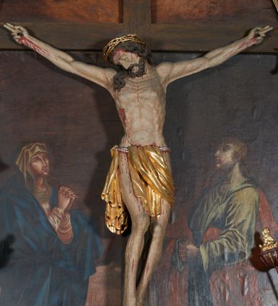 Zdjęcie nr 1: Krucyfiks w typie Christo morte; postać  Chrystusa umarłego przybitego do krzyża trzema gwoździami. Sylwetka w delikatnym zwisie, o silnie zaznaczonej anatomii ciała, z podkreśloną linią żeber i zaznaczonymi śladami męki. Perizonium w formie tkaniny przewiązanej na sznurze, sięgające kolan i odsłaniające prawe udo; z prawej strony spływające kaskadowo. Twarz Jezusa podłużna opadająca na prawe ramię, okolona zarostem; oczy zamknięte, nos podłużny, wystające kości policzkowe; włosy długie spływające na prawe ramię, na głowie złota korona cierniowa. Partie ciała polichromowane naturalistycznie, korona cierniowa i perizonium złocone.