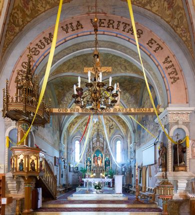 Zdjęcie nr 12: Prezbiterium jest węższe od nawy, zamknięte trójbocznie, oddziela je tęcza o łuku półkolistym z napisem „EGO SUM VIA VERITAS ET VITA”. Od zachodu chór na dwóch filarach, zamknięty balustradą dekorowaną płycinami. Ściany wnętrza dzielą pilastry podtrzymujące gurty sklepienia i łuki arkad, a dekoruje polichromia ze scenami biblijnymi i wizerunkami świętych. Sklepienie krzyżowo-żebrowe. Ściany przeprute oknami – prezbiterium dwoma, transept sześcioma, nawa czterema, kolejne w wieży i rotundach. Niemal wszystkie  kształcie stojącego prostokąta zamkniętego łukiem pełnym, kolejne; większość wypełniają witraże. Główne wejście przez korpus wieżowy od zachodu, kolejne do obu ramion transeptu i przybudówek. Fasada wieżowa, z wejściem przez portal z archiwoltami, z kolumienkami po bokach, ujęty ściśle szerokimi , ustawionymi skośnie szkarpami zwieńczonymi tympanonami i kapnikami. Powyżej portalu trójdzielne okno w kształcie smukłych, stojących prostokątów, a nad nim prostokątne zamknięte łukiem pełnym. Wyżej tarcza zegara w szerokiej ramie, zamontowana w szczycie. Wyżej wieża przechodzi w ośmiobok o czterech ścianach zwieńczonych ostrołukowo i przeprutych oknami i ściętych narożach między nimi.  Masyw wieży flankują wieloboczne ćwierćrotundy z arkadami ujętymi kolumientami w górnej partii i dekoracją kostkową pod linią dachu.  Z zewnątrz bryła kościoła jest rozczłonkowana, o ścianach wspartych przyporami z kapnikami i fryzem arkadkowym pod linią dachu. Wszystkie dachy blaszane; nad nawą, transeptem i przybudówkami dwuspadowe, nad prezbiterium zamknięty wielobocznie. Wieżę przykrywa wieloboczny, wyjątkowo wysoki dach namiotowy, nad rotundami wieloboczne.  Całe wyposażenie jest spójne, powstało około 1900 roku i zostało wykonane w stylu neogotyckim. 