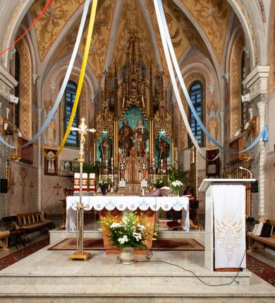 Zdjęcie nr 11: Prezbiterium jest węższe od nawy, zamknięte trójbocznie, oddziela je tęcza o łuku półkolistym z napisem „EGO SUM VIA VERITAS ET VITA”. Od zachodu chór na dwóch filarach, zamknięty balustradą dekorowaną płycinami. Ściany wnętrza dzielą pilastry podtrzymujące gurty sklepienia i łuki arkad, a dekoruje polichromia ze scenami biblijnymi i wizerunkami świętych. Sklepienie krzyżowo-żebrowe. Ściany przeprute oknami – prezbiterium dwoma, transept sześcioma, nawa czterema, kolejne w wieży i rotundach. Niemal wszystkie  kształcie stojącego prostokąta zamkniętego łukiem pełnym, kolejne; większość wypełniają witraże. Główne wejście przez korpus wieżowy od zachodu, kolejne do obu ramion transeptu i przybudówek. Fasada wieżowa, z wejściem przez portal z archiwoltami, z kolumienkami po bokach, ujęty ściśle szerokimi , ustawionymi skośnie szkarpami zwieńczonymi tympanonami i kapnikami. Powyżej portalu trójdzielne okno w kształcie smukłych, stojących prostokątów, a nad nim prostokątne zamknięte łukiem pełnym. Wyżej tarcza zegara w szerokiej ramie, zamontowana w szczycie. Wyżej wieża przechodzi w ośmiobok o czterech ścianach zwieńczonych ostrołukowo i przeprutych oknami i ściętych narożach między nimi.  Masyw wieży flankują wieloboczne ćwierćrotundy z arkadami ujętymi kolumientami w górnej partii i dekoracją kostkową pod linią dachu.  Z zewnątrz bryła kościoła jest rozczłonkowana, o ścianach wspartych przyporami z kapnikami i fryzem arkadkowym pod linią dachu. Wszystkie dachy blaszane; nad nawą, transeptem i przybudówkami dwuspadowe, nad prezbiterium zamknięty wielobocznie. Wieżę przykrywa wieloboczny, wyjątkowo wysoki dach namiotowy, nad rotundami wieloboczne.  Całe wyposażenie jest spójne, powstało około 1900 roku i zostało wykonane w stylu neogotyckim. 