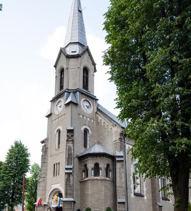 Zdjęcie nr 26: Prezbiterium jest węższe od nawy, zamknięte trójbocznie, oddziela je tęcza o łuku półkolistym z napisem „EGO SUM VIA VERITAS ET VITA”. Od zachodu chór na dwóch filarach, zamknięty balustradą dekorowaną płycinami. Ściany wnętrza dzielą pilastry podtrzymujące gurty sklepienia i łuki arkad, a dekoruje polichromia ze scenami biblijnymi i wizerunkami świętych. Sklepienie krzyżowo-żebrowe. Ściany przeprute oknami – prezbiterium dwoma, transept sześcioma, nawa czterema, kolejne w wieży i rotundach. Niemal wszystkie  kształcie stojącego prostokąta zamkniętego łukiem pełnym, kolejne; większość wypełniają witraże. Główne wejście przez korpus wieżowy od zachodu, kolejne do obu ramion transeptu i przybudówek. Fasada wieżowa, z wejściem przez portal z archiwoltami, z kolumienkami po bokach, ujęty ściśle szerokimi , ustawionymi skośnie szkarpami zwieńczonymi tympanonami i kapnikami. Powyżej portalu trójdzielne okno w kształcie smukłych, stojących prostokątów, a nad nim prostokątne zamknięte łukiem pełnym. Wyżej tarcza zegara w szerokiej ramie, zamontowana w szczycie. Wyżej wieża przechodzi w ośmiobok o czterech ścianach zwieńczonych ostrołukowo i przeprutych oknami i ściętych narożach między nimi.  Masyw wieży flankują wieloboczne ćwierćrotundy z arkadami ujętymi kolumientami w górnej partii i dekoracją kostkową pod linią dachu.  Z zewnątrz bryła kościoła jest rozczłonkowana, o ścianach wspartych przyporami z kapnikami i fryzem arkadkowym pod linią dachu. Wszystkie dachy blaszane; nad nawą, transeptem i przybudówkami dwuspadowe, nad prezbiterium zamknięty wielobocznie. Wieżę przykrywa wieloboczny, wyjątkowo wysoki dach namiotowy, nad rotundami wieloboczne.  Całe wyposażenie jest spójne, powstało około 1900 roku i zostało wykonane w stylu neogotyckim. 