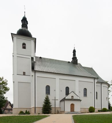 Zdjęcie nr 3: Kościół usytuowany jest w centrum miejscowości, na północny-zachód od drogi prowadzącej z Orawki do Spytkowic. Plac kościelny otoczony jest żeliwnym płotem na kamiennej podmurówce. Główne wejście prowadzi od strony zachodniej; drugie, mniejsze od strony południowej. 

Kościół orientowany, jednonawowy z emporami w części zachodniej, podtrzymywanymi przez arkady, które tworzą dodatkowe przejścia; prezbiterium krótkie i węższe od nawy, zamknięte półkoliście, od północny przylega do niego niewielka zakrystia. Główne wejście do kościoła znajduje się od strony zachodniej przez czworoboczny przedsionek, nad którym wznosi się wieża, drugie wejście przez kruchtę od strony południowej nawy. Kościół jest oświetlony przez  sześć podłużnych okien zamkniętych półkoliście oraz dwóch takich samych w prezbiterium, ponadto na wschodniej ścianie prezbiterium dwa niewielkie, okrągłe otwory okienne. Wnętrze artykułowane jest pilastrami wspierającymi gurty sklepienne, w ostatnim wschodnim przęśle nawy półkoliste arkady tworzące pseudotransept. Chór muzyczny wsparty na trzech arkadach, zamkniętych łukiem odcinkowym, analogiczne dwie pary arkad wspierają empory po bokach nawy. Sklepienie w nawie trójprzęsłowe, kolebkowe na gurtach, w prezbiterium jednoprzęsłowe.

Elewacja kościoła w dolnej części z kamienną okładziną, wyżej kościół tynkowany, artykułowany lizenami. Fasada zachodnia trójosiowa, w osi środkowej wysunięta do przodu trójkondygnacyjna wieża, flankowana lizenami. W drugiej kondygnacji na osiach bocznych fasady spływy flankujące wieżę, za którymi schowany jest dach nad nawą. Wieża nakryta hełmem baniastym z latarnią. Na zakończeniu nawy wieżyczka na sygnaturkę, nakryta analogicznym, mniejszym hełmem z latarnią. Dach nad nawą dwuspadowy, nad prezbiterium, nad kruchtą siodłowy. Na przyczółku kruchty umieszczona jest w głębokiej wnęce, zamkniętej łukiem odcinkowym rzeźba Matki Boskiej z Dzieciątkiem, a nad wejściem zachodnim do świątyni rzeźba św. Wojciecha.



