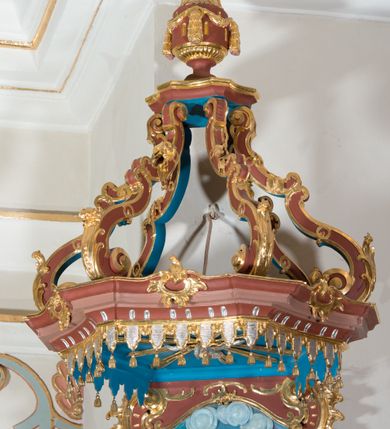 Zdjęcie nr 6: Ambona przyścienna, wisząca ustawiona przy północnej ścianie, dostępna jednobiegowymi schodami z balustradą od strony prezbiterium. Kosz na planie sześcioboku u dołu z ćwierćwałkiem, zdobionym na narożach dekoracją rokokową; u góry zamknięty profilowanym gzymsem. Ścianki artykułowane spływami wolutowymi o karbowanych trzonach. W polach prostokątne płyciny mieszczące płaskorzeźbione rocaille. Podwieszenie w formie stożka o wklęsło-wypukłych bokach, zakończonego płaskorzeźbioną rozetą. Ścianki flankowane w narożach analogicznie jak kosz, w polach trapezoidalne płyciny, przerwane pośrodku okręgiem z rozetką. Zaplecek prostokąty ujęty płaskim obramieniem o zgeometryzowanych wolutach w dolnych narożach oraz rocaille'm w górnych. Pośrodku płaskorzeźbione przedstawienie św. Jana Chrzciciela na tle pejzażu. Baldachim powtarzający plan kosza, zwieńczony wazonem ustawionym na sześciu spiętych kabłąkach. W podniebiu gołębica Ducha Świętego na tle promienistej glorii, na brzegach zawieszony lambrekin. Balustrada schodów pełna, od dołu ujęta półwałkiem, zamknięta profilowanym gzymsem, w polu dwie  płyciny w kształcie rombów, w których umieszczone są rocaille. Balustrada zakończona filarkiem, na którym ustawiony jest wazonik. Całość struktury ambony polichromowana w odcieniach brązu, płaskorzeźba wielobarwna, profilowania i detal architektoniczny pozłacany, podniebienie baldachimu malowane na niebiesko, lambrekin posrebrzany.

