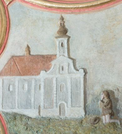 Zdjęcie nr 4: Płaskorzeźba ujęta w fantazyjną ramę utworzoną z zawijających się do środka wolut w kształcie litery „C” spiętych palmetami. Pośrodku ukazany św. Izydor Oracz stojący frontalnie w lekkim rozkroku z prawą ręką wspartą o laskę, lewą złożoną na piersi. Twarz szeroka, okolona krótką brodą. Święty ubrany jest w krótkie, czerwone spodnie, sukmanę sięgająca kolan oraz kapelusz, na stopach ma pełne, brązowe buty. Po prawej stronie kompozycji, u stóp  świętego  klęczący anioł. W tle pejzaż z bryłą kościoła w Podwilku i klęczącą przed nim postacią ukazaną po lewej stronie, natomiast po prawej pług zaprzężony do dwóch wołów, prowadzony przez anioła. Polichromia w odcieniach pastelowych, tunika i kapelusz świętego brązowy, kościół biały nakryty czerwonym dachem. Obramienie polichromii malowane na czerwono, pośrodku złocone, palmety malowane na niebiesko i złocone. Poniżej płaskorzeźby pole w kształcie leżącego prostokąta o wklęsłych narożach z napisem „Labore praeCIpVe pIIs eXpenIs sVbDlicae pLebIs hVIVs / paroChIae s VbViLkensIs haeC saCra aeDes feLICIter / sVrreXIt”.
