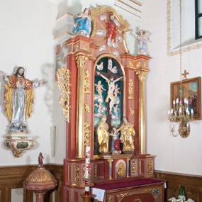 Zdjęcie nr 1: Nastawa ołtarzowa przyścienna, architektoniczna, jednoosiowa, jednokondygnacyjna ze zwieńczeniem. Ołtarz skrzyniowy, prostopadłościenny z kamiennym portatylem w drewnianej ramie. Antepedium drewniane, zdobione płyciną, w której umieszczony jest monogram Chrystusa. W narożach płaskorzeźbiony ornament akantowy z kratką oraz nałożonymi narzędziami męki Pańskiej: po lewej stronie czerwona suknia, o którą rzucano losy, po prawej stronie niebieska rękawica Malchusa. Tabernakulum (współczesne) w formie prostopadłościennej szafki flankowanej parą wolnostojących kolumienek o korynckich kapitelach, podtrzymujących profilowany gzyms płyty nakrywającej całość obiektu. Drzwiczki w formie zbliżonej do kwadratu zamknięte półkoliście, zdobione płaskorzeźbioną dekoracją ukazującą fragment postaci Chrystusa złożonego w grobie oraz motywu cierni, kwiatów i symboli eucharystycznych – kielich i chleb. Całość wkomponowana w dwa nakładające się na siebie koła. 

Retabulum ustawione na wysokim, zdwojonym, uskokowym cokole. Nastawa ujęta parą kolumn korynckich. Kolumny wspierają przerwane, wyłamane ponad nimi belkowanie z wysuniętym gzymsem.  Pola środkowe w formie prostokątnej wnęki zamkniętej półkoliście, ujętej profilowaną ramą. Wewnątrz pola rzeźbiona grupa Ukrzyżowania, w skład której wchodzi krucyfiks oraz figury Matki Boskiej, św. Jana Ewangelisty oraz św. Marii Magdaleny. Tło przedstawienia stanowi malarski pejzaż Jerozolimy oraz płaskorzeźbione figurki czterech aniołków i dwóch uskrzydlonych  główek anielskich wśród srebrzonych obłoków. W partii fryzu motyw stylizowanej palmety. Po bokach nastawy uszy z liści akantu oplatające kratkę regencyjną. W pionowych polach flankujących główną scenę ołtarza ornamentyka roślinna liści akantu z rozetami, pomiędzy nimi motyw kwiatu róży. 

Zwieńczenie o formie wklęsło-wypukłej, ujęte dekoracyjnymi spływami o formach roślinnych. W polu rzeźbione przedstawienie Boga Ojca na tle obłoków i promieni oraz figury dwóch aniołów usytuowanych na wysuniętych partiach belkowania po bokach zwieńczenia. Polichromia całości struktury ołtarza w odcieniach brązu, profilowania, detal architektoniczny i ornamentyka złocone i srebrzone.  
