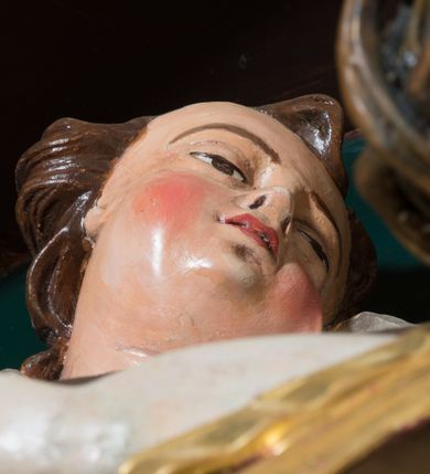 Zdjęcie nr 3: Pełnoplastyczna, polichromowana figura Chrystusa w typie Cristo morte przybitego trzema gwoździami do  dużego, brązowego krzyża. Chrystus ukazany w statycznej pozie, w mocnym zwisie z ugiętymi w kolanach nogami. Twarz podłużna z długim nosem, okolona krótką brodą, która na końcu zawija się w dwa pukle. Włosy długie, ciemnobrązowe opadające na prawe ramię i plecy. Sylwetka szczupła o wyraźnie podkreślonej linii żeber z guzowatą klatką piersiową; na głowie, kolanach, dłoniach, stopach i boku ślady krwi.  Perizonium przewiązane na prawym boku ze zwisem wzdłuż prawego uda, złocone. Na głowie szeroka korona cierniowa, wokół niej niekompletny nimb krzyżowy z jedną wiązką promieni. Kolorystyka ciała utrzymana w odcieniach bladego  beżu. U góry pionowej belki posrebrzany titulus w formie pionowej pogiętej banderoli z napisem: „IN / RI”. Krucyfiks otaczają cztery aniołki na obłokach o teatralnych gestach, nad krzyżem dwie uskrzydlone główki anielskie. Tło malowane na kolor ciemnoniebieski. Polichromia w odsłoniętych partiach ciała naturalistyczna, detale złocone i srebrzone.