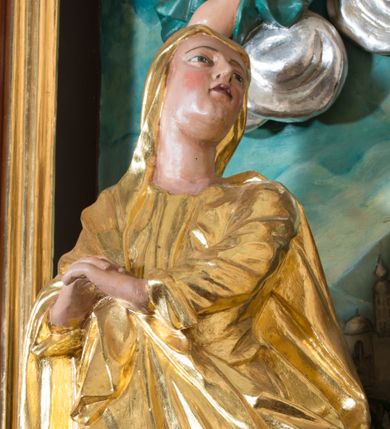 Zdjęcie nr 1: Rzeźba Matki Boskiej wydrążona, umiejscowiona na niewielkim, prostopadłościennym cokole. Ukazana w pozycji stojącej w znacznym kontrapoście, z prawą nogą ugiętą w kolanie, ze splecionymi dłońmi uniesionymi na wysokości piersi z prawej strony. Głowa skierowana ku górze, zwrócona w trzech czwartych w lewo. Twarz pełna o jasnoróżowej karnacji z zarumienionymi policzkami, oczy zwrócone ku górze. Maria ubrana jest w długą, złoconą suknię oraz złocony płaszcz, okrywający głowę, plecy i prawe ramię, podwinięty pod lewą ręką. Na stopach ma brązowe, szpiczaste buciki. Polichromia w odsłoniętych partiach ciała naturalistyczna, szaty złocone.