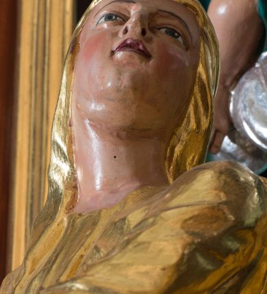 Zdjęcie nr 3: Rzeźba Matki Boskiej wydrążona, umiejscowiona na niewielkim, prostopadłościennym cokole. Ukazana w pozycji stojącej w znacznym kontrapoście, z prawą nogą ugiętą w kolanie, ze splecionymi dłońmi uniesionymi na wysokości piersi z prawej strony. Głowa skierowana ku górze, zwrócona w trzech czwartych w lewo. Twarz pełna o jasnoróżowej karnacji z zarumienionymi policzkami, oczy zwrócone ku górze. Maria ubrana jest w długą, złoconą suknię oraz złocony płaszcz, okrywający głowę, plecy i prawe ramię, podwinięty pod lewą ręką. Na stopach ma brązowe, szpiczaste buciki. Polichromia w odsłoniętych partiach ciała naturalistyczna, szaty złocone.