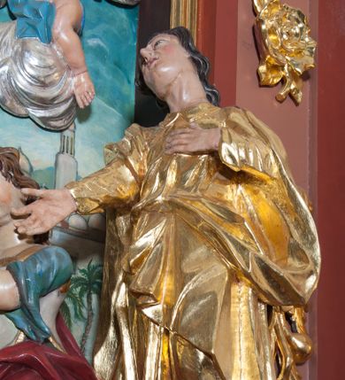 Zdjęcie nr 1: Rzeźba drążona, polichromowana, umiejscowiona na niewielkim, prostopadłościennym cokole. Święty Jan w ujęciu całopostaciowym, w pozycji stojącej, w kontrapoście z głową uniesioną ku górze i lekko odchyloną do tyłu i w prawo. Twarz owalna o mocno zarysowanym podbródku, nos długi, lekko zadarty, szpiczasty, usta niewielkie, lekko rozchylone, oczy zwrócone ku górze. Włosy długie, brązowe, falowane, opadające na plecy. Lewa dłoń wsparta na piersiach, prawa wyciągnięta ku przodowi. Święty ubrany jest w długą, fałdowaną, przewiązaną w pasie suknię z kołnierzykiem pod szyją, spod niej widoczne bose stopy. Na niej płaszcz przerzucony, przez prawe ramię i przełożony przez pasek podtrzymujący suknię. Polichromia w odsłoniętych partiach ciała naturalistyczna, szaty złocone.