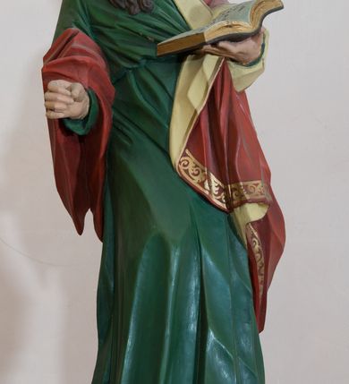 Zdjęcie nr 3: Rzeźba drążona, przedstawiająca św. Pawła. Święty ustawiony na niskim, brązowym cokole, frontalnie, w kontrapoście, o esowato wygiętej sylwetce, z prawą nogą ugiętą w kolanie, głową zwróconą w lewo. W lewej dłoni trzyma otwartą księgę, natomiast prawą ma wysuniętą do przodu i ułożoną do niezachowanego atrybutu (miecza). Twarz owalna z zarumienionymi policzkami z dużym nosem, okolona ciemnobrązową, gęstą i długą brodą. Włosy średniej długości, ciemnobrązowe, zasłaniają uszy. Ubrany jest w długą w zieloną suknię oraz czerwony płaszcz z beżową podszewką, założony na lewe ramię i przerzucony jedną połą przez prawe przedramię. Płaszcz na brzegach zdobiony jest złoconą dekoracją ornamentalną, a suknia u dołu dekorowana ornamentem złożonym ze złączonych trójliści. Polichromia w odsłoniętych partiach ciała naturalistyczna, detale złocone. 