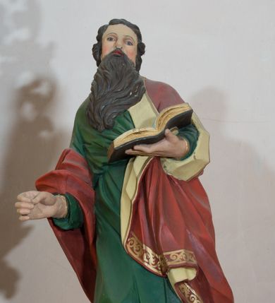 Zdjęcie nr 1: Rzeźba drążona, przedstawiająca św. Pawła. Święty ustawiony na niskim, brązowym cokole, frontalnie, w kontrapoście, o esowato wygiętej sylwetce, z prawą nogą ugiętą w kolanie, głową zwróconą w lewo. W lewej dłoni trzyma otwartą księgę, natomiast prawą ma wysuniętą do przodu i ułożoną do niezachowanego atrybutu (miecza). Twarz owalna z zarumienionymi policzkami z dużym nosem, okolona ciemnobrązową, gęstą i długą brodą. Włosy średniej długości, ciemnobrązowe, zasłaniają uszy. Ubrany jest w długą w zieloną suknię oraz czerwony płaszcz z beżową podszewką, założony na lewe ramię i przerzucony jedną połą przez prawe przedramię. Płaszcz na brzegach zdobiony jest złoconą dekoracją ornamentalną, a suknia u dołu dekorowana ornamentem złożonym ze złączonych trójliści. Polichromia w odsłoniętych partiach ciała naturalistyczna, detale złocone. 