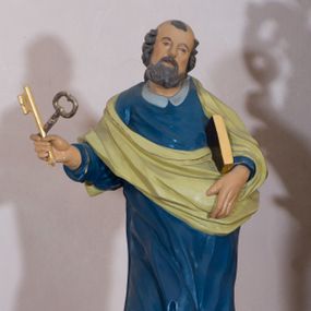 Zdjęcie nr 1: Rzeźba drążona, przedstawiająca św. Piotra. Święty ustawiony na niskim cokole, w delikatnym kontrapoście, z prawą nogą ugiętą w kolanie, z rozłożonymi na boki stopami. W prawej dłoni trzyma dwa skrzyżowane klucze, a w lewej księgę w brązowej oprawie. Twarz podłużna, okolona siwą brodą z długim nosem i małymi ustami. Włosy siwe, zasłaniające uszy, głowa ujęta do połowy łysiną, nad czołem kosmyk siwych włosów. Święty jest ubrany w długą, niebieską suknię z kołnierzykiem, u dołu zdobioną złoconym pasem ornamentu składającego się ze złączonych trójliści. Na suknię ma założony zwinięty jasnozielony płaszcz. Polichromia w odsłoniętych partiach ciała naturalistyczna, detale i klucze złocone.
