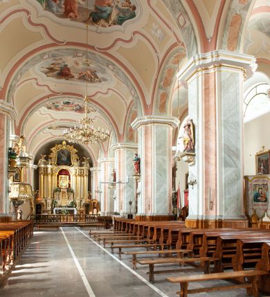 Zdjęcie nr 5: Kościół usytuowany jest w centrum miejscowości na północ od głównej drogi. Na plac kościelny prowadzi główne wejście od strony wschodniej. Świątynia skierowana jest na północ, założona na planie prostokąta z wieżą w fasadzie z prezbiterium zamkniętym trójbocznie, węższym od nawy. Za prezbiterium dobudowana jest kaplica na planie prostokąta, a od zachodu zakrystia. Główne wejście do kościoła znajduje się od strony południowej. 

Wnętrze trójnawowe, halowe, czteroprzęsłowe; nawy oddzielone arkadami na opliastrowanych filarach o wklęsłych narożnikach wspierających sklepienie żaglaste na gurtach. Chór muzyczny wsparty na trzech arkadach filarowych. Balustrada na rzucie wklęsło-wypukłym z uskokami. Wnętrze nawy jest oświetlone przez dziesięć, niskich, zamkniętych półkoliście okien, w prezbiterium cztery analogiczne okna. 

Fasada z ryzalitem w osi środkowej, ujętym zdwojonymi pilastrami, zwieńczonym przerwanym przyczółkiem, na osi portal i balkon z półkoliście zamkniętym oknem. W szczycie fasady drugi przyczółek, w polu monogram maryjny, a poniżej napis: „AVE MARIA GRATIA PLENA DOMINVS TECTVM”. Wyżej na osi czworoboczna wieża, opięta pilastrami w narożach, zwieńczona baniastym hełmem z latarnią. Korpus nawowy o zaokrąglonych narożnikach z podziałami ramowymi i oknami termalnymi. Prezbiterium i kaplica opięte szkarpami. Nad prezbiterium i nawą oddzielne dachy, dwuspadowe. 
